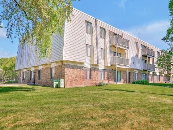 Exterior view of a multi-unit apartment building with balconies and green lawn.