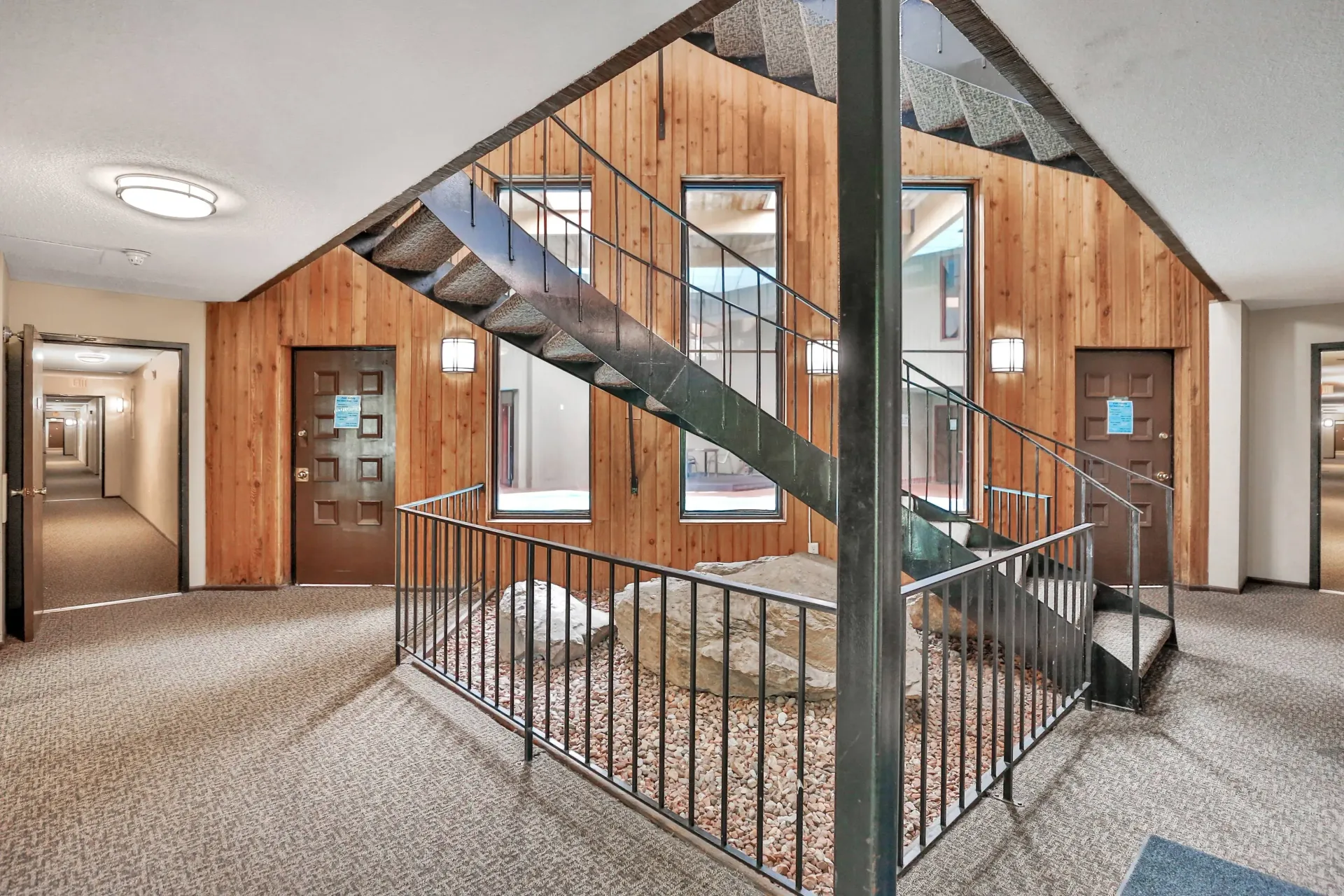 Interior of an apartment building with a wood-paneled wall and metal staircase at Eagle Point Apartments in West St. Paul, MN.
