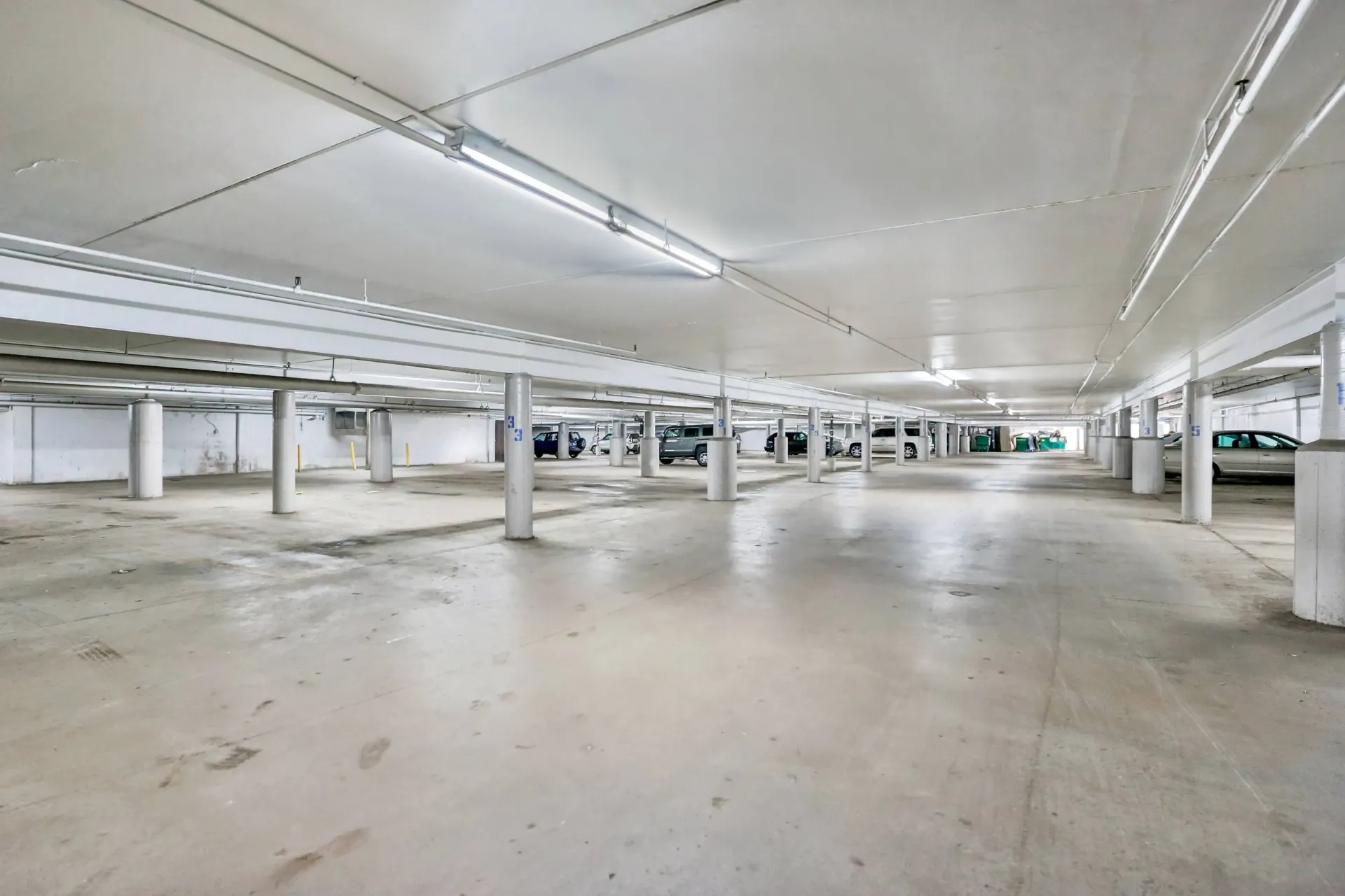 Empty, white-walled parking garage with support columns and overhead lights at Eagle Point Apartments in West St. Paul, MN.