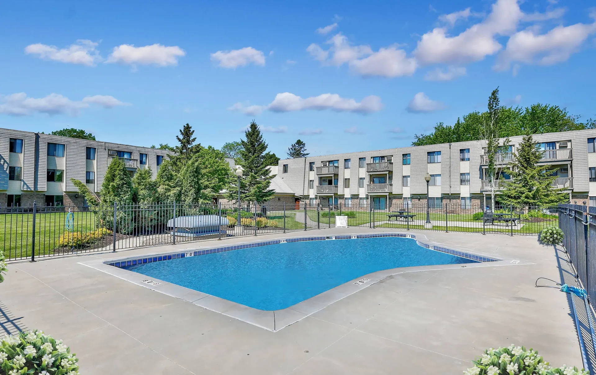 Swimming pool in front of multi-unit buildings under a blue sky at Eagle Point Apartments in West St. Paul, MN.