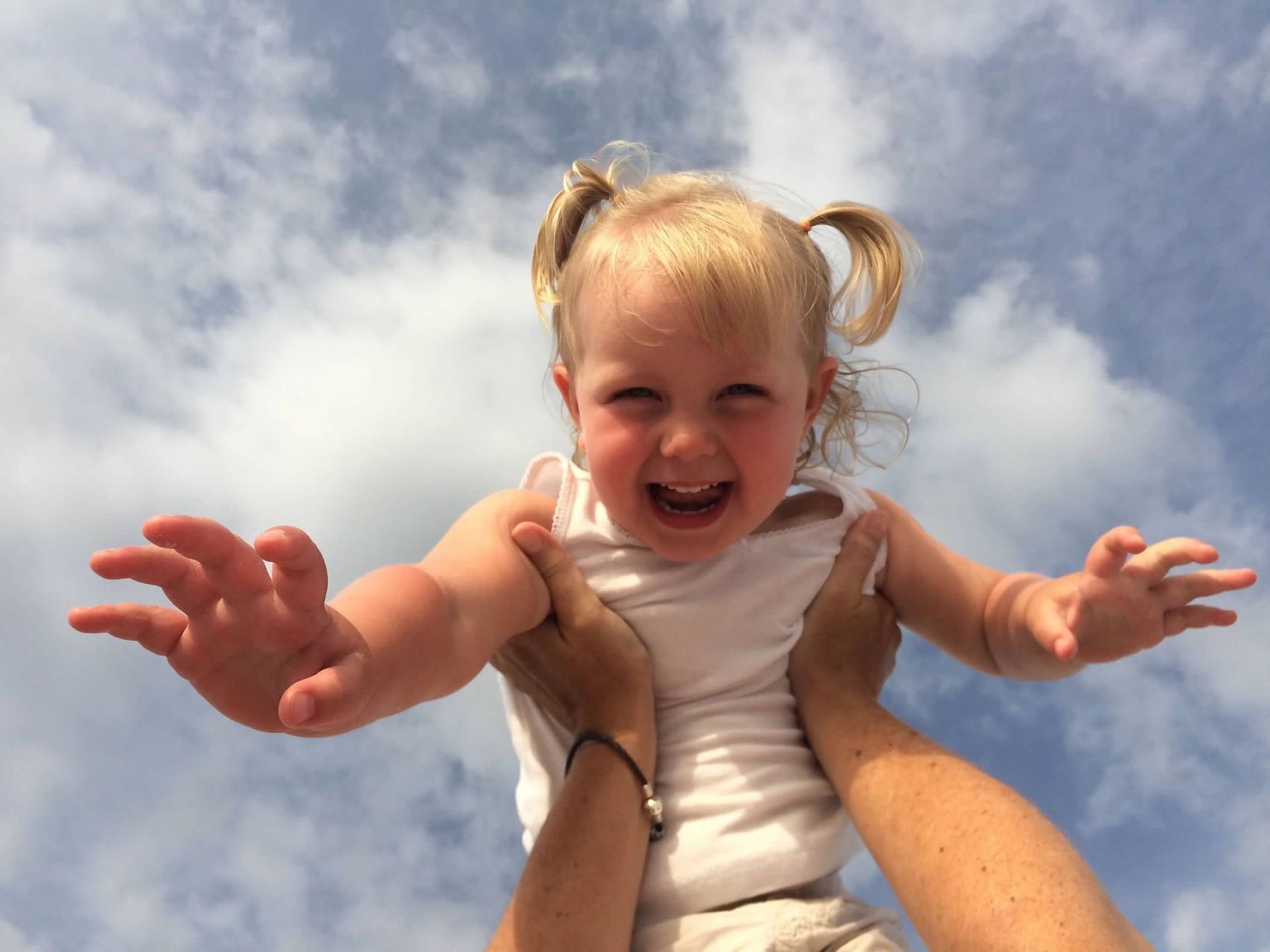 A little girl is being held up in the air by a person