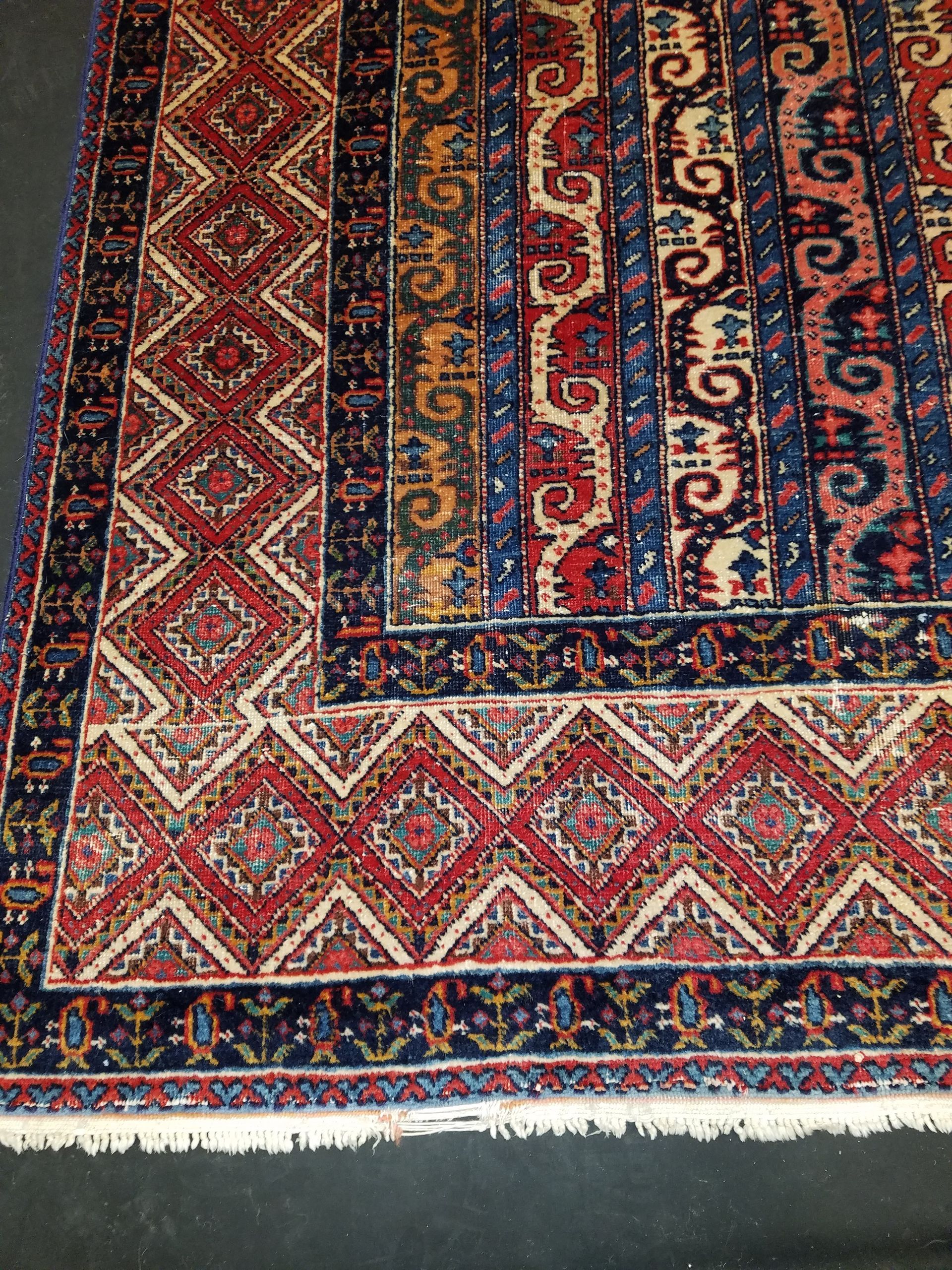 Close-up of a vibrant, patterned rug with red, blue, and gold geometric designs.
