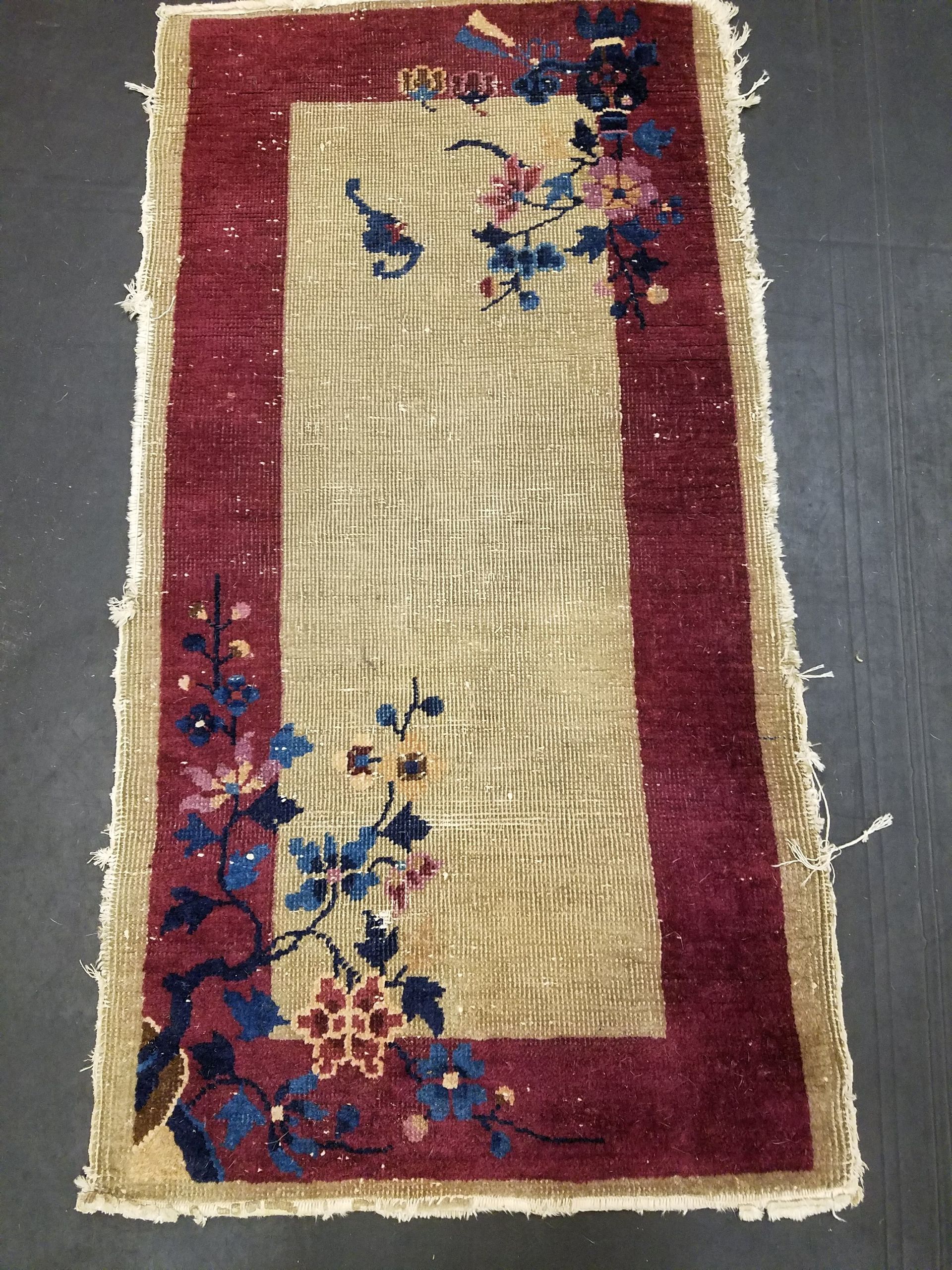 Small rectangular rug with burgundy border, beige center, and floral designs in pink, blue, and burgundy.