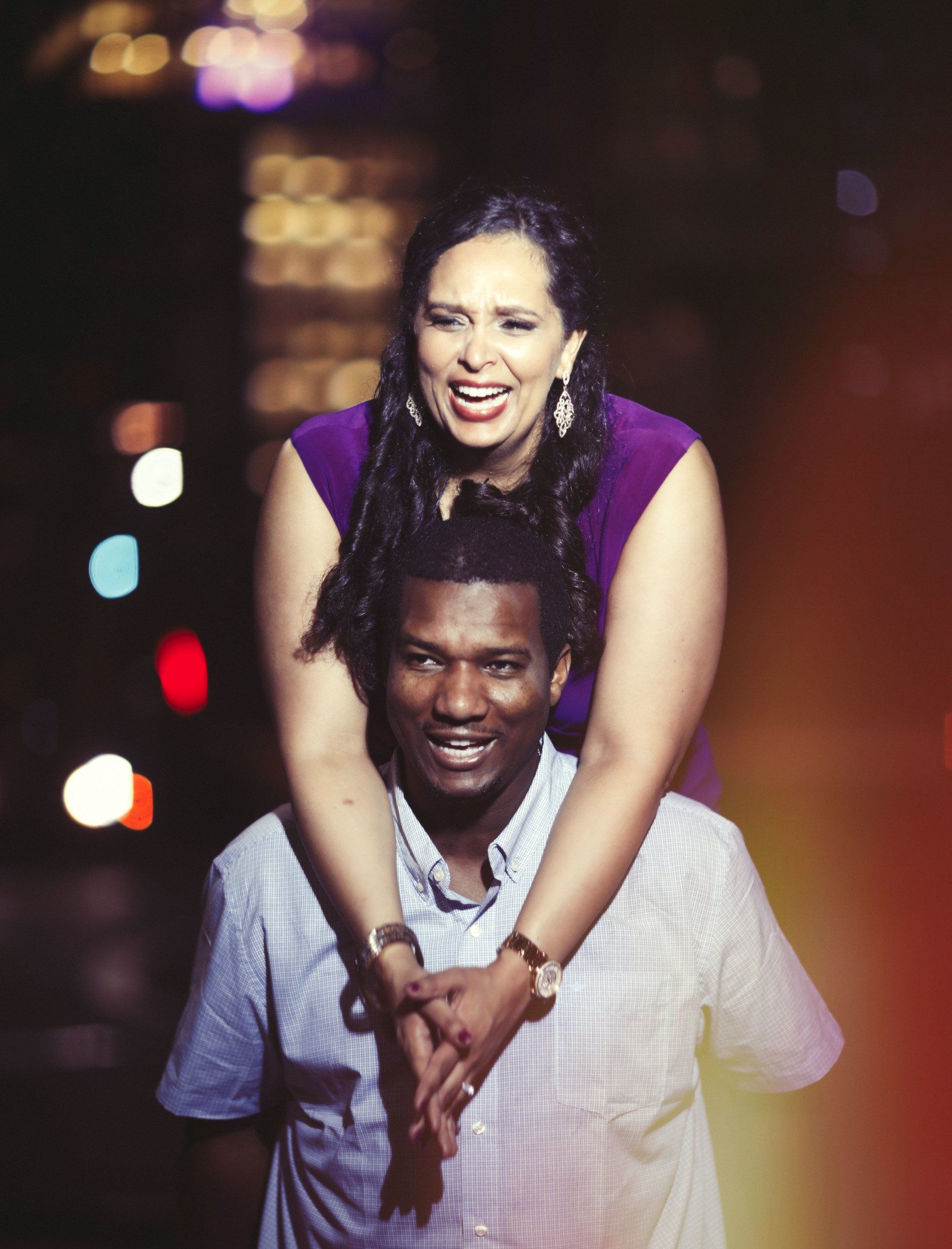 A woman is sitting on a man 's shoulders and smiling