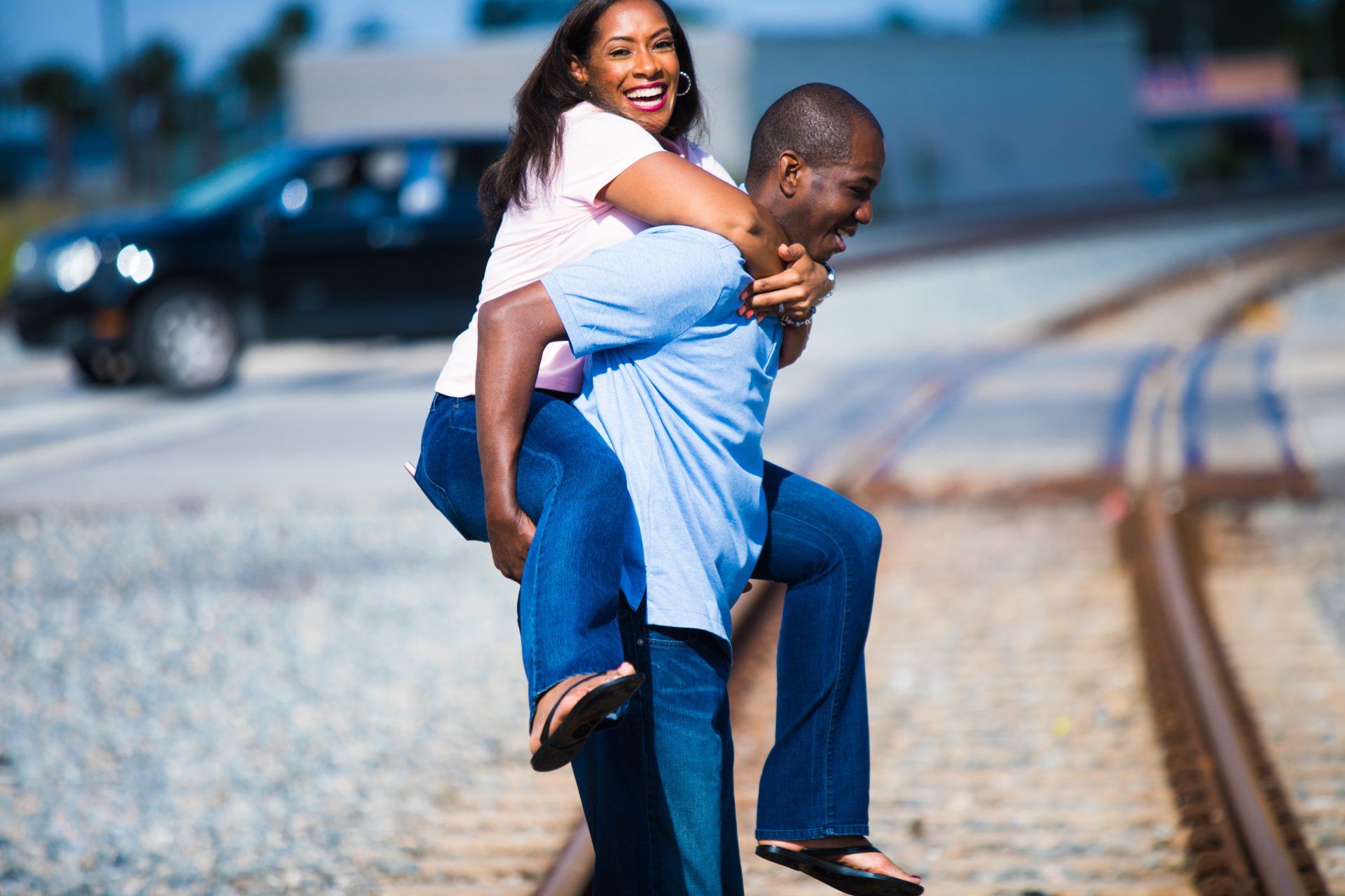 A man is carrying a woman on his back on train tracks