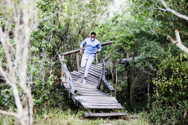 A man is walking across a wooden bridge in the woods.
