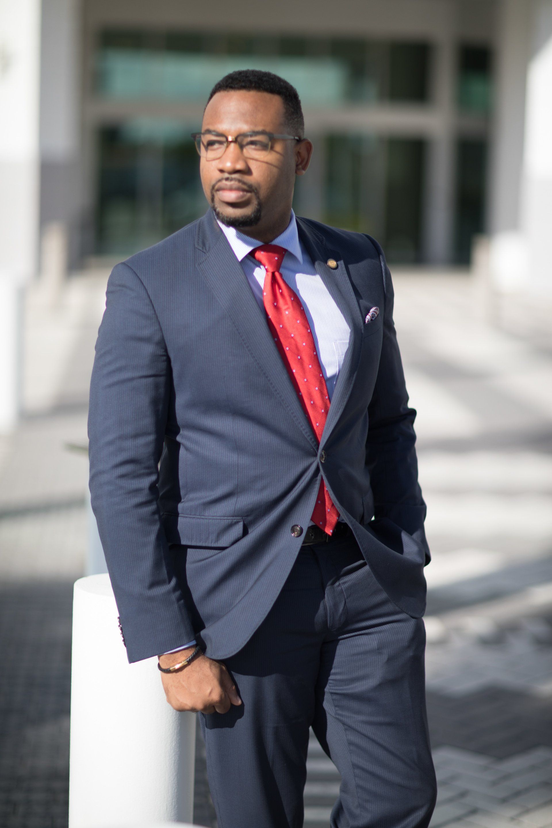 A man in a suit and tie is leaning against a pole.