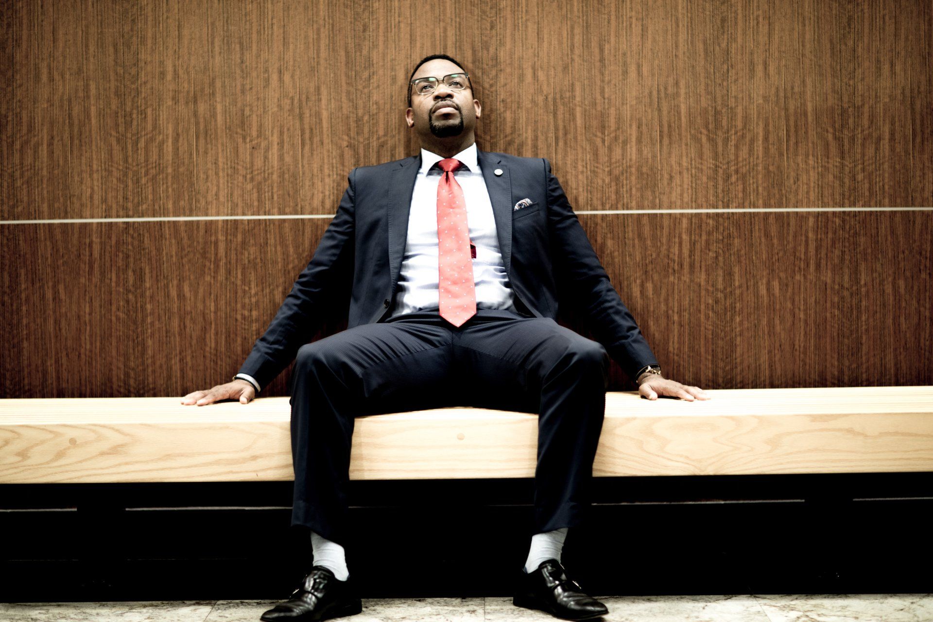 A man in a suit and tie is sitting on a wooden bench.