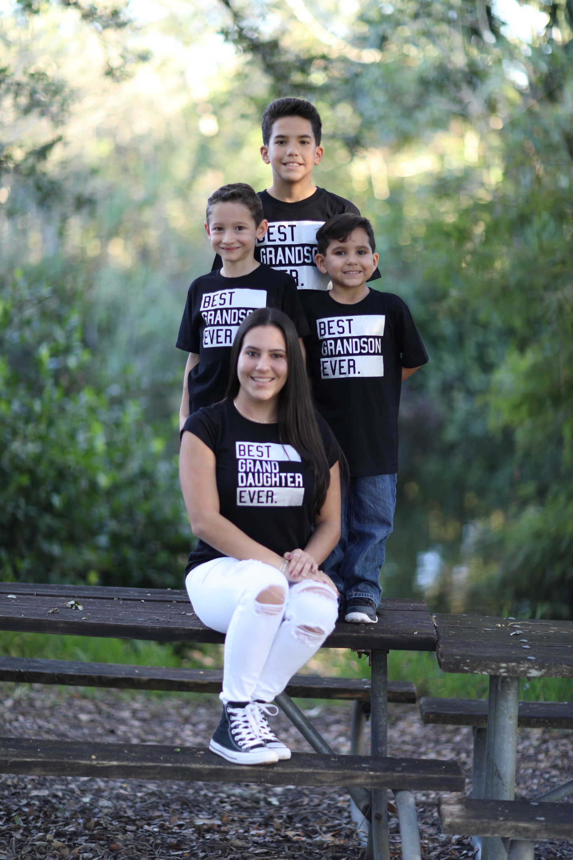 A woman is sitting on a picnic table with three children.