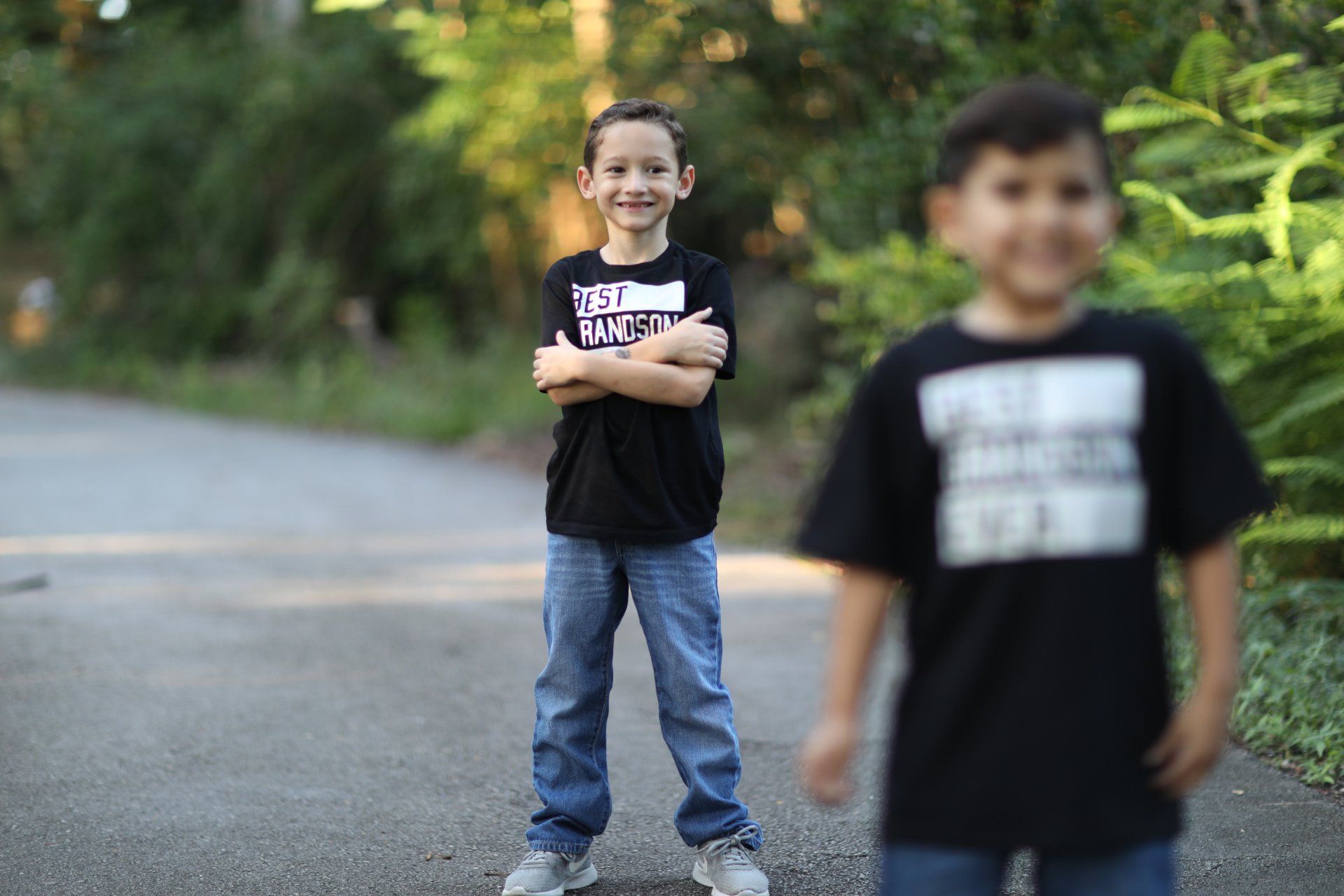 Two young boys are standing next to each other on a road.