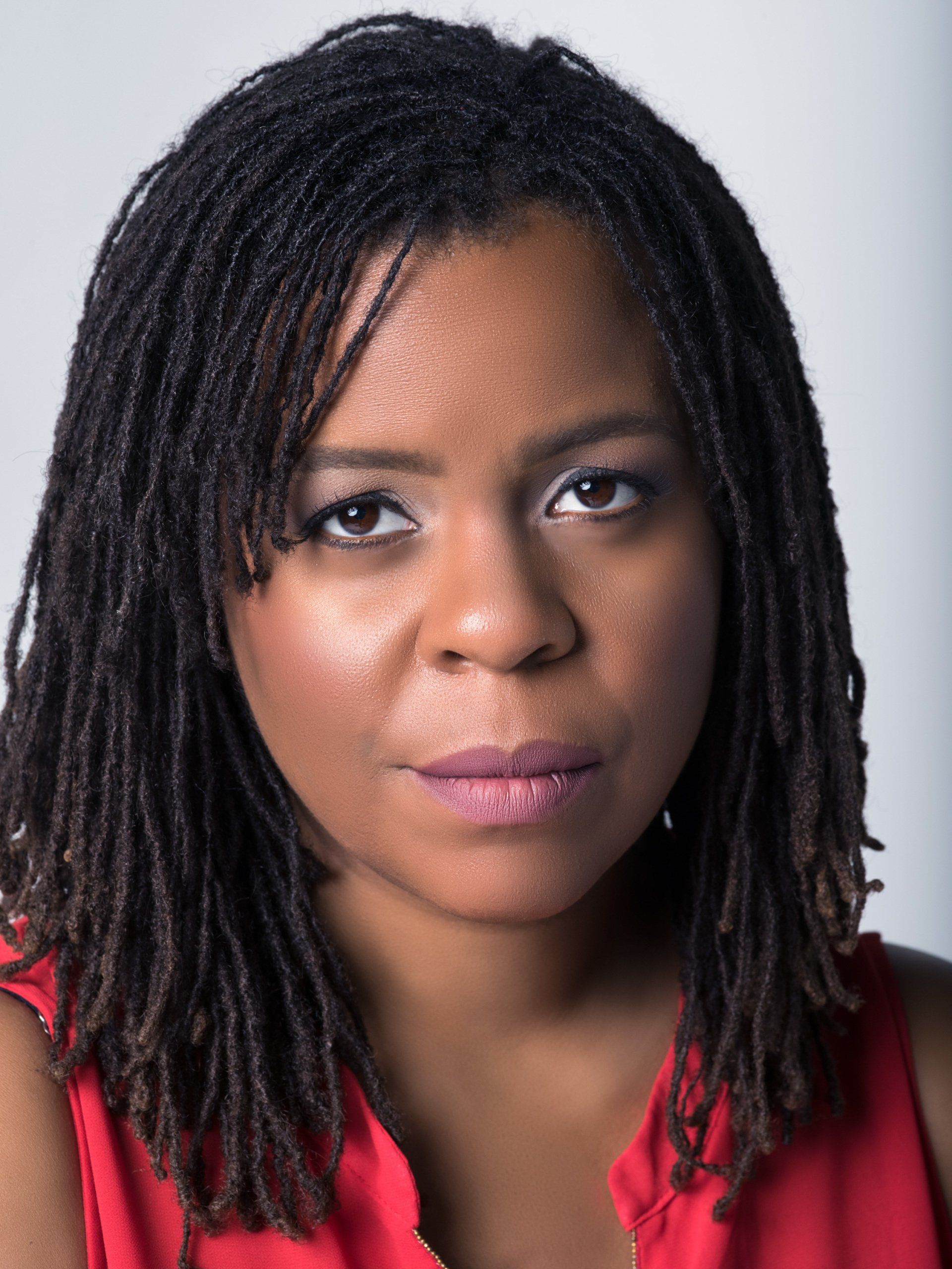 A woman with dreadlocks is wearing a red shirt