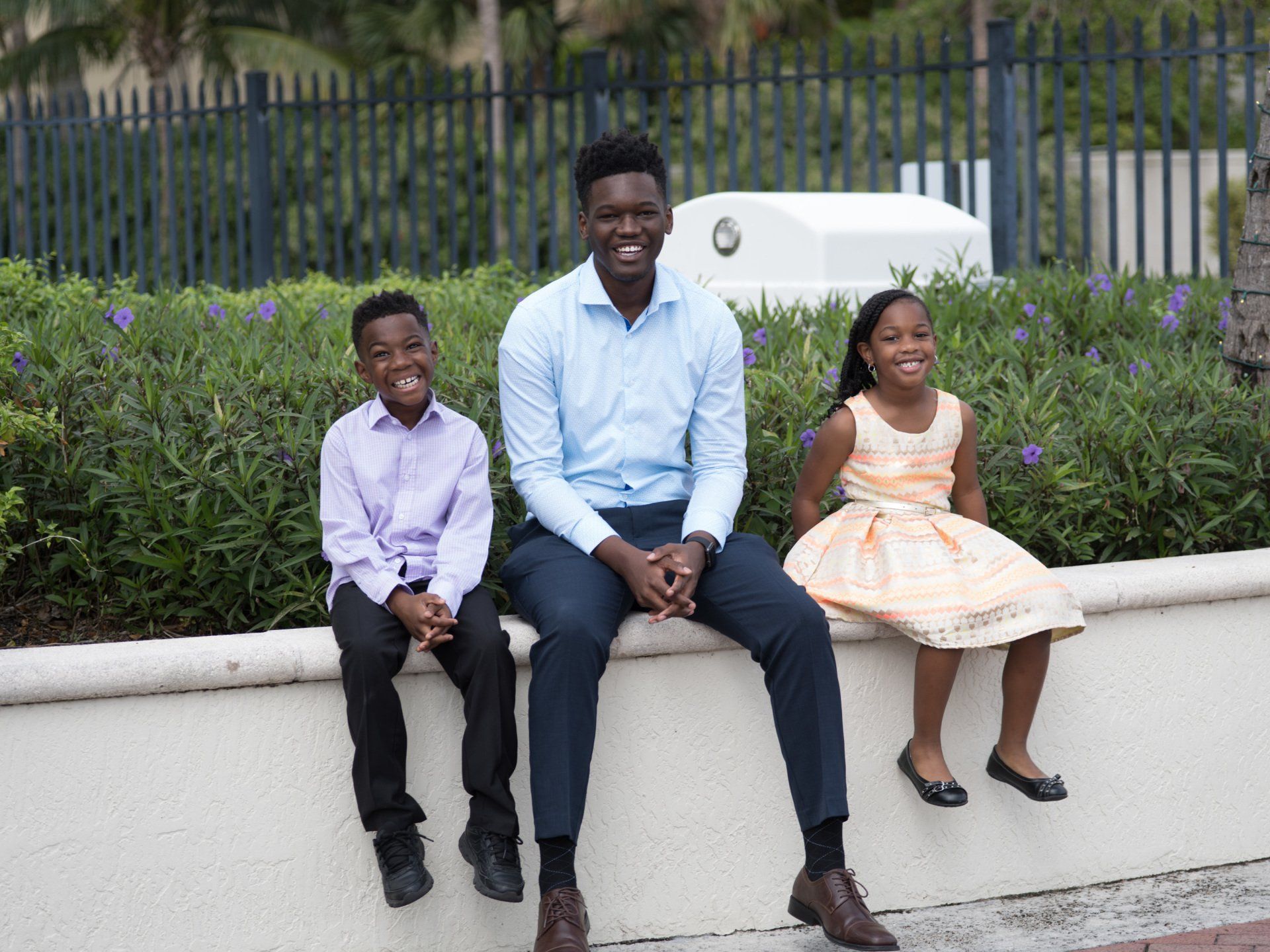 A man and two children are sitting on a wall.