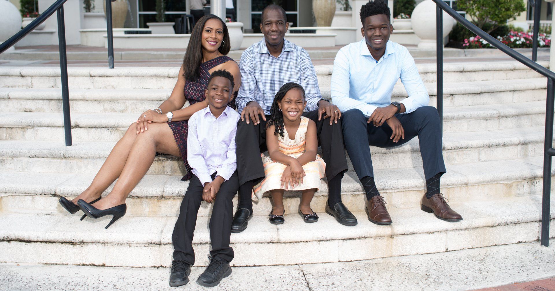 A family is sitting on the steps of a building.