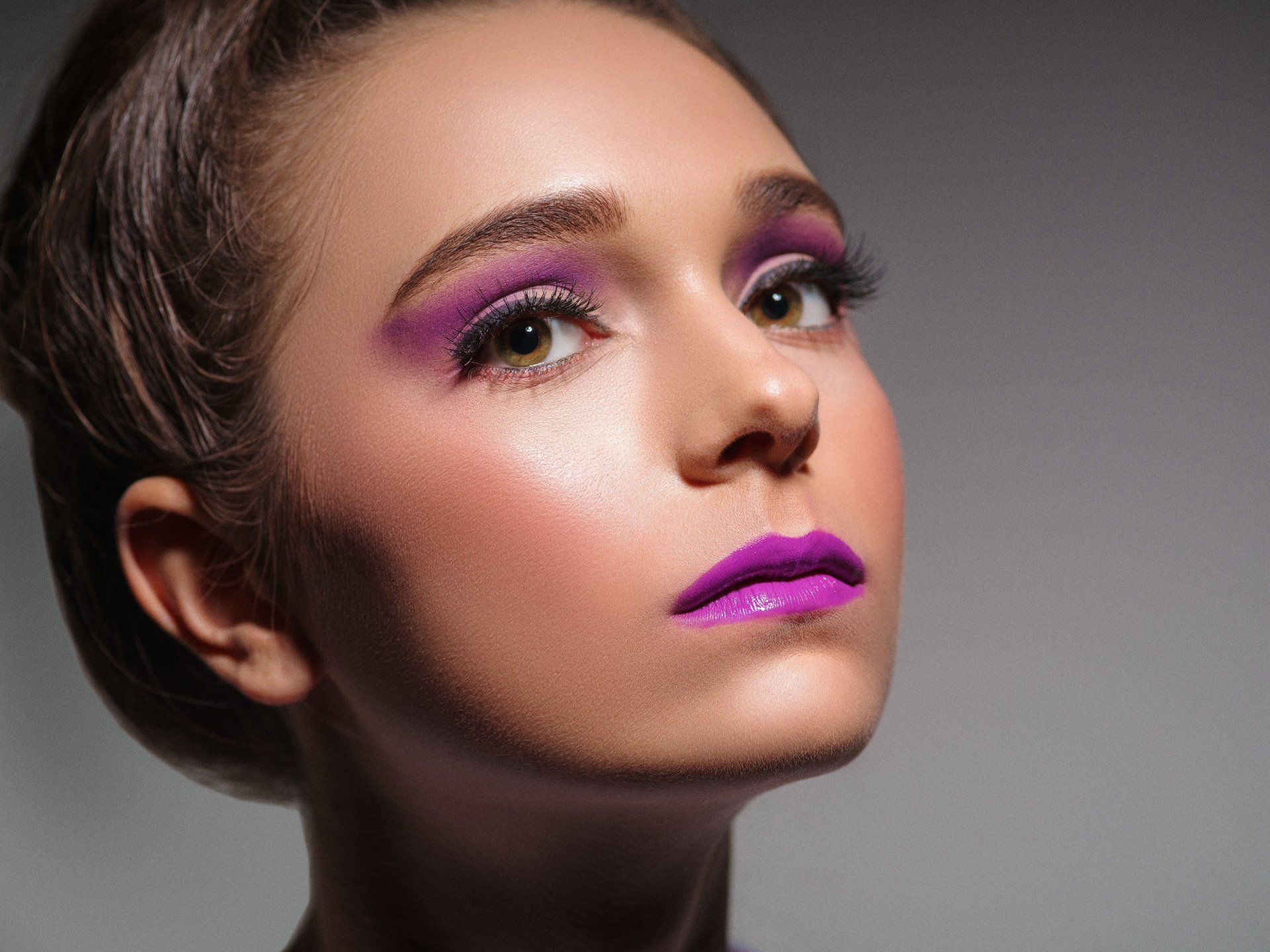 A close up of a woman 's face with purple makeup.