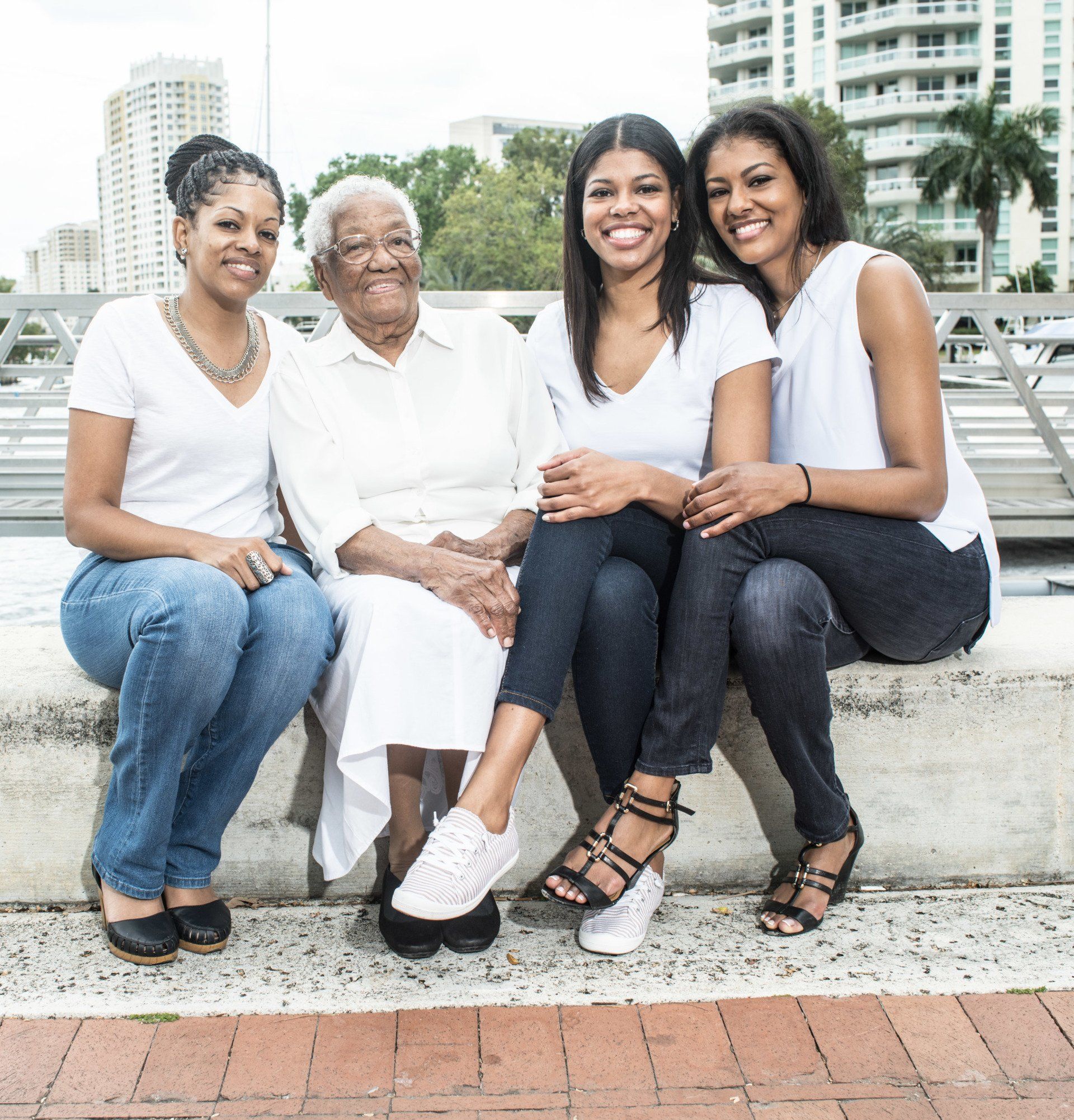Four women are posing for a picture while sitting on a bench