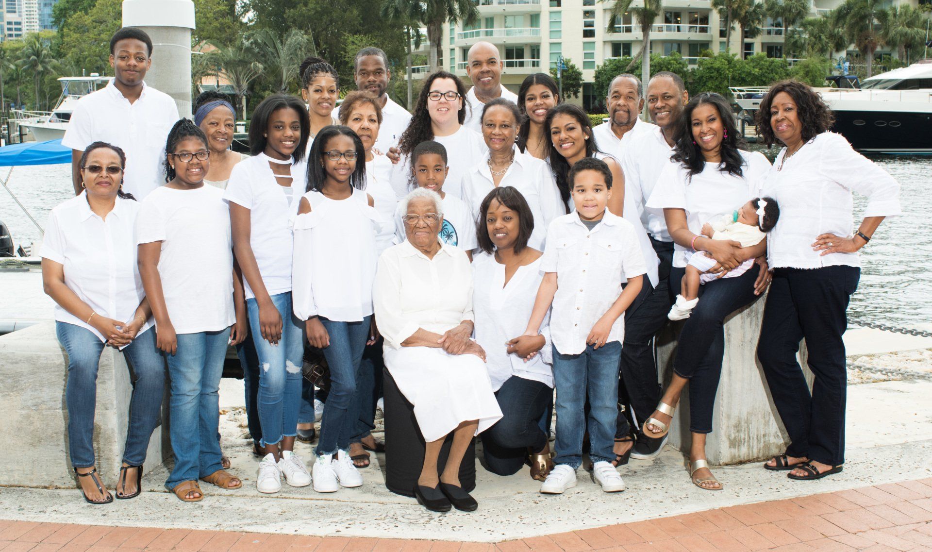 A large family is posing for a picture in front of a body of water.