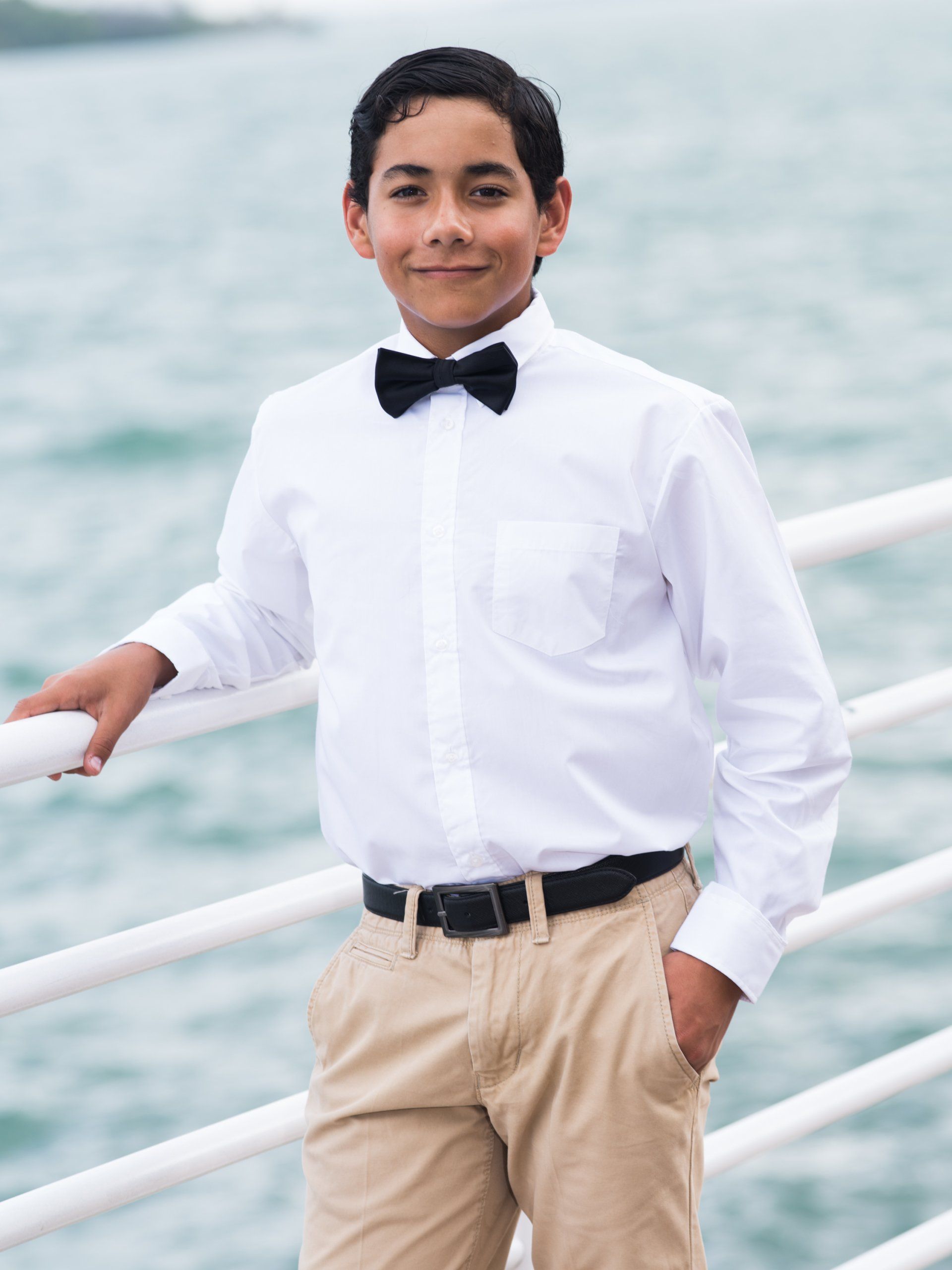 A young boy wearing a white shirt and a black bow tie