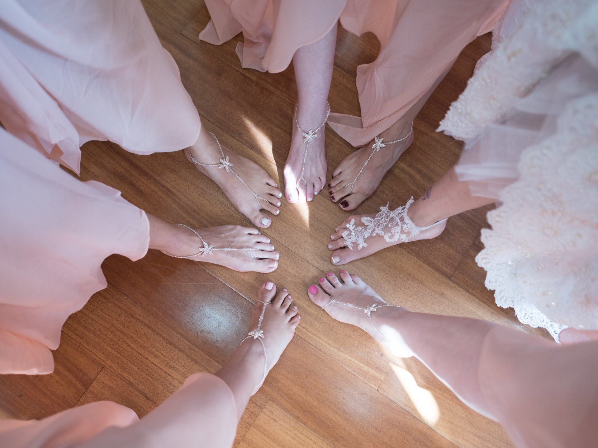 A group of women 's feet are in a circle on a wooden floor.
