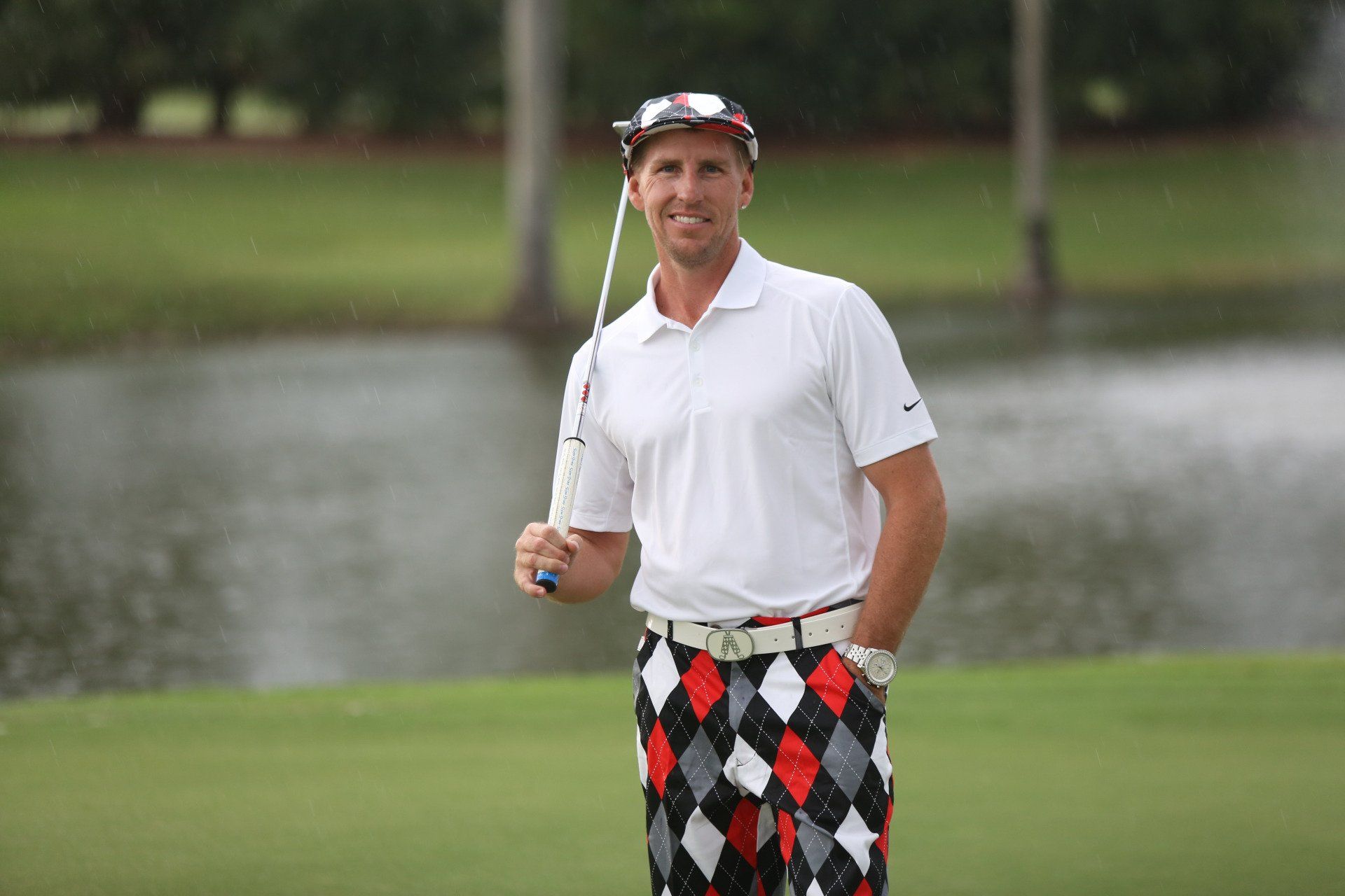 A man is standing on a golf course holding a golf club.