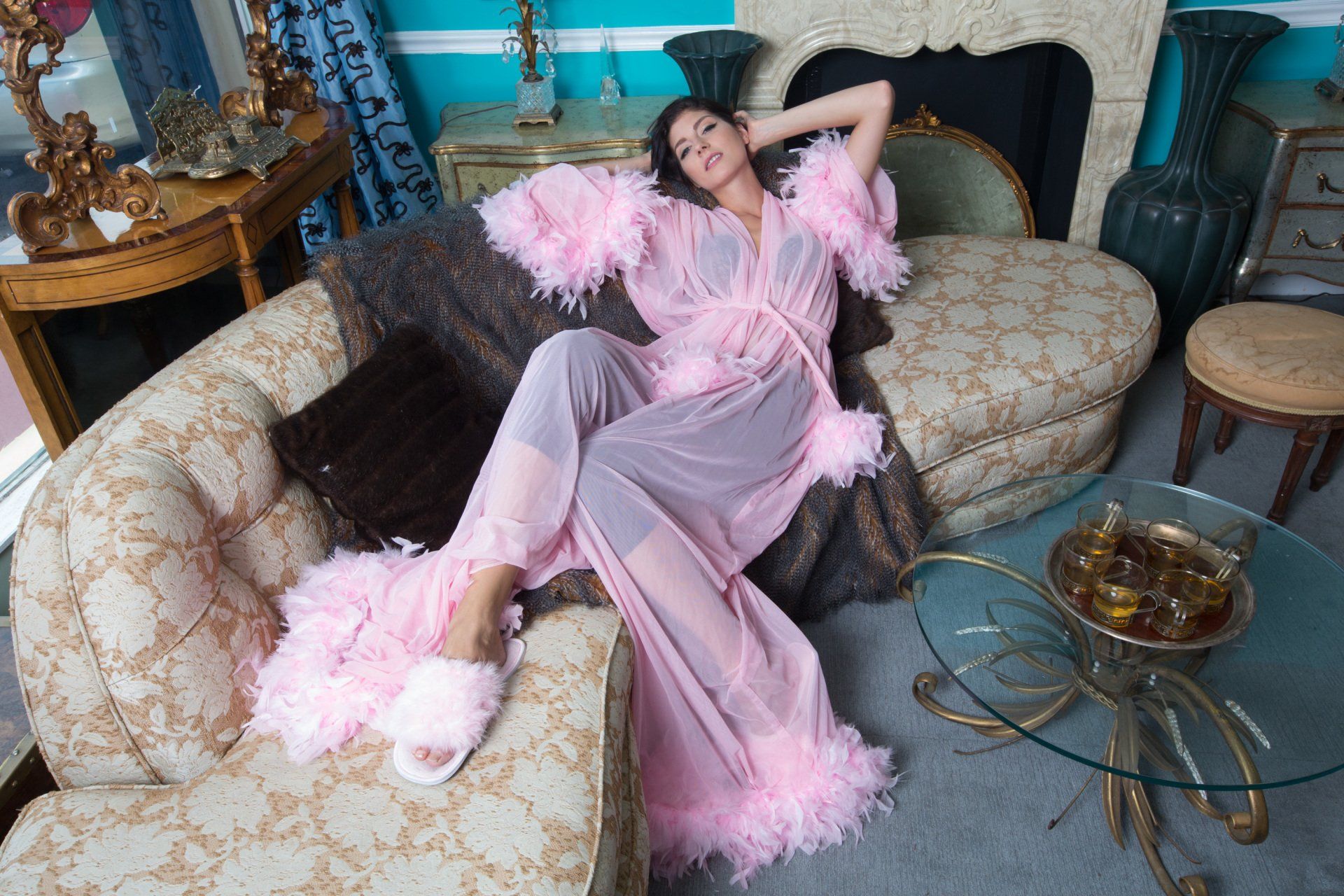 A woman in a long pink robe is sitting on a couch.