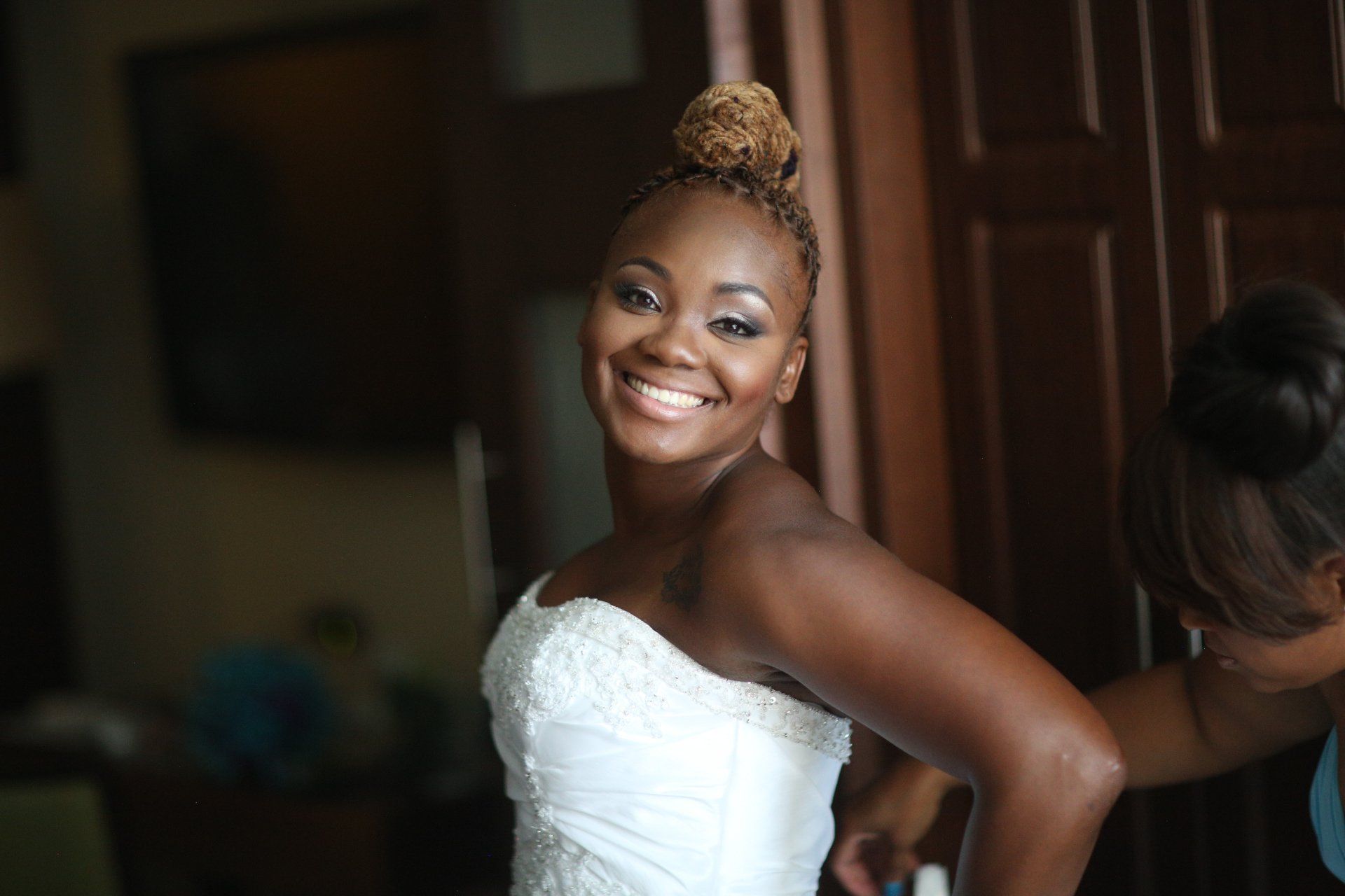 A woman in a wedding dress is smiling while getting ready for her wedding.
