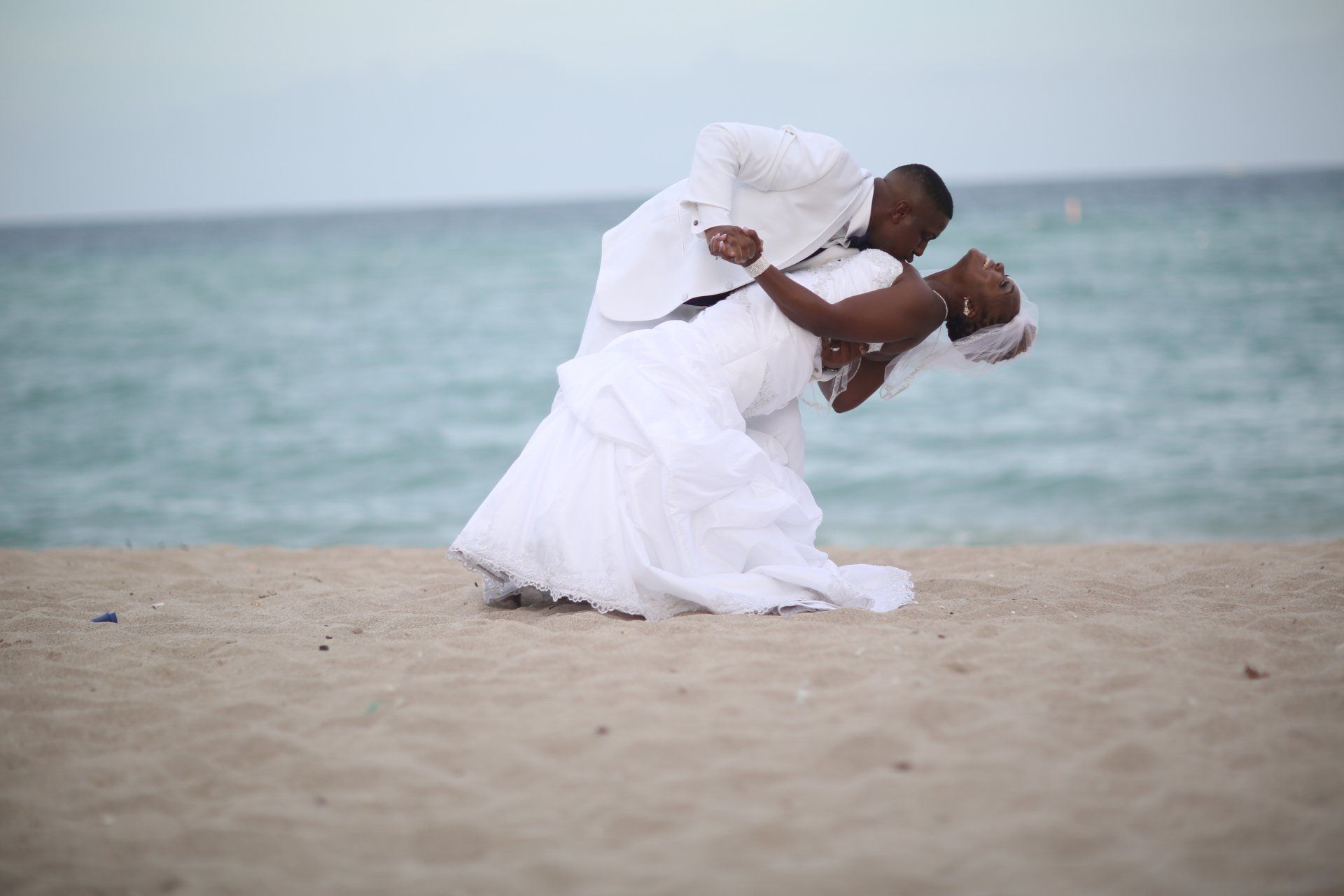 A bride and groom are dancing on the beach.