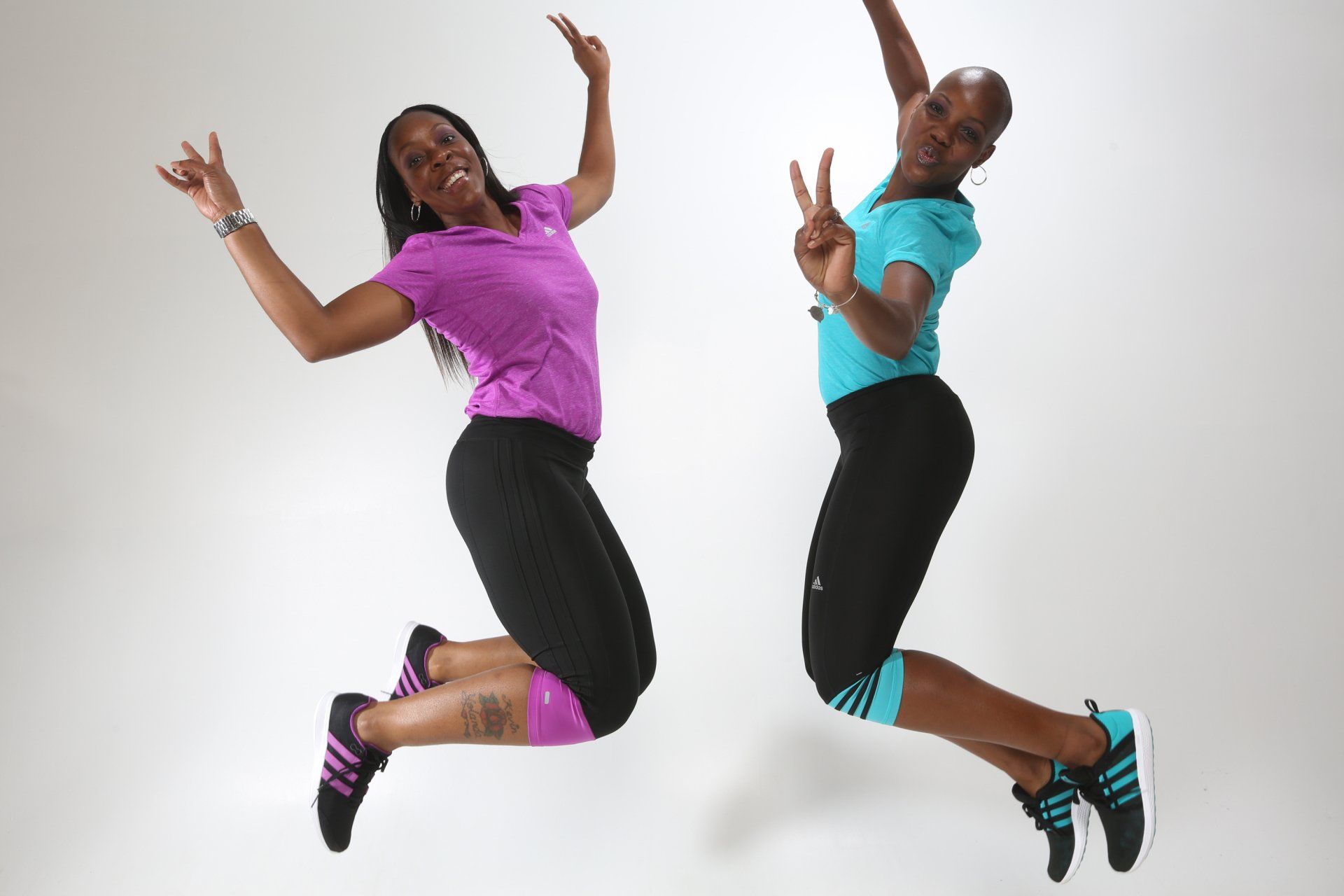Two women are jumping in the air with their arms outstretched