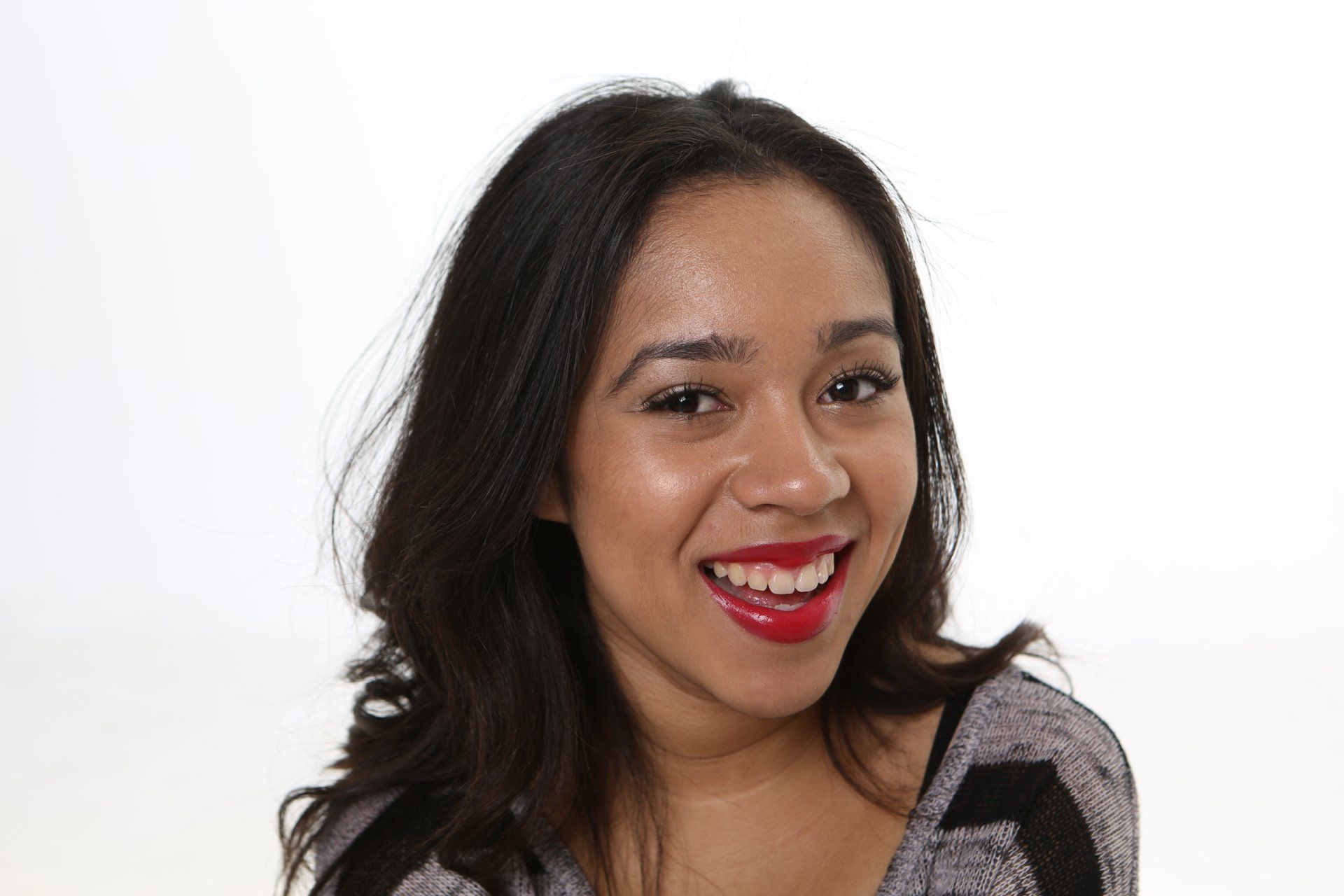 A woman with red lipstick on her lips is smiling for the camera.