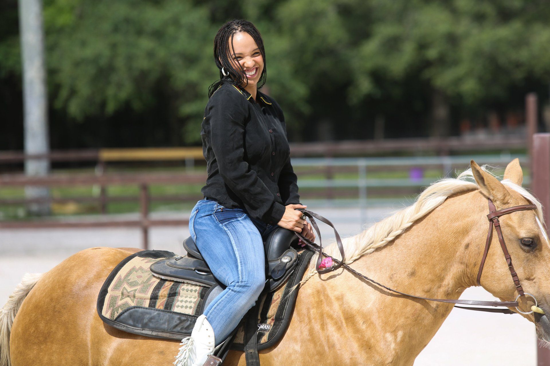 A woman is riding a horse in a fenced in area.