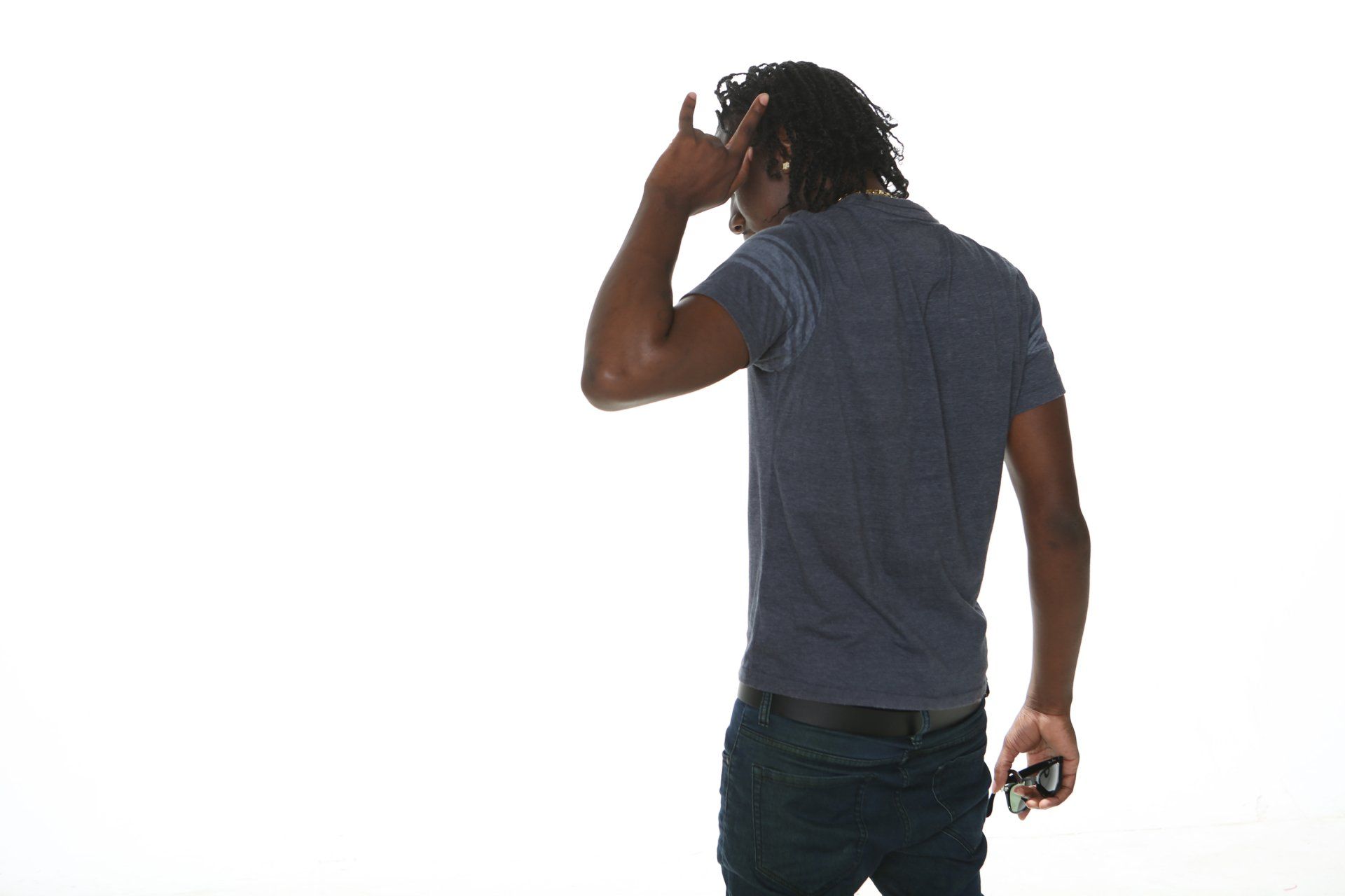 A man wearing headphones is standing in front of a white background.
