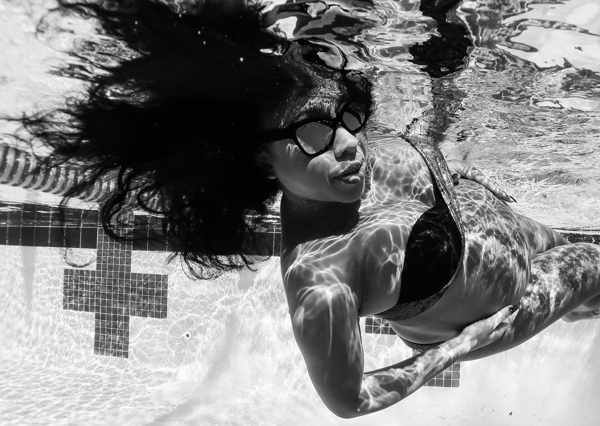 A woman in a bikini is swimming underwater in a pool.