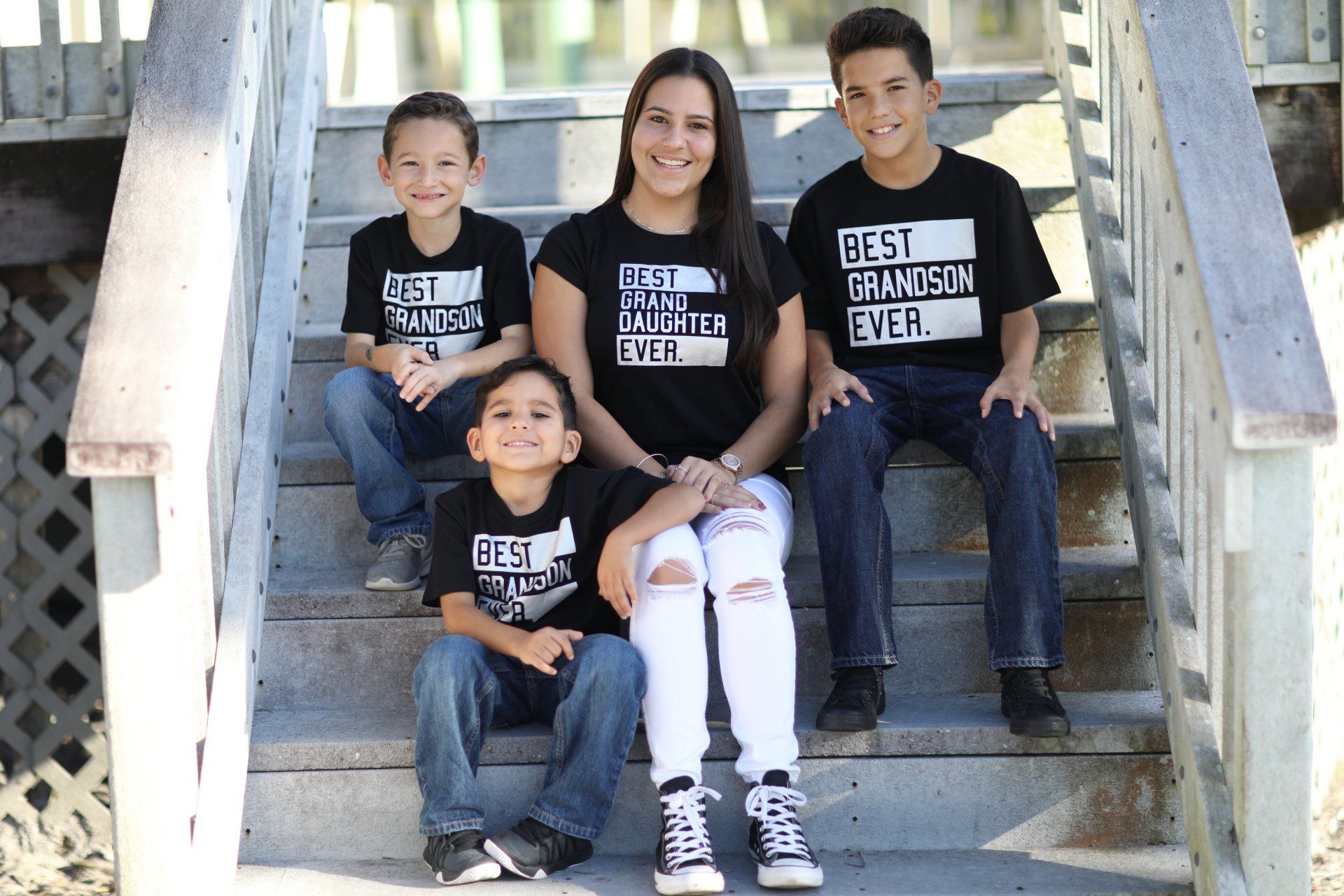 A woman and three children are sitting on a set of stairs.