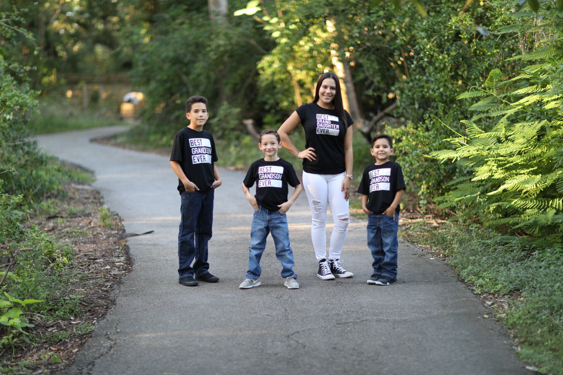 A woman and three children are standing on a path in the woods.