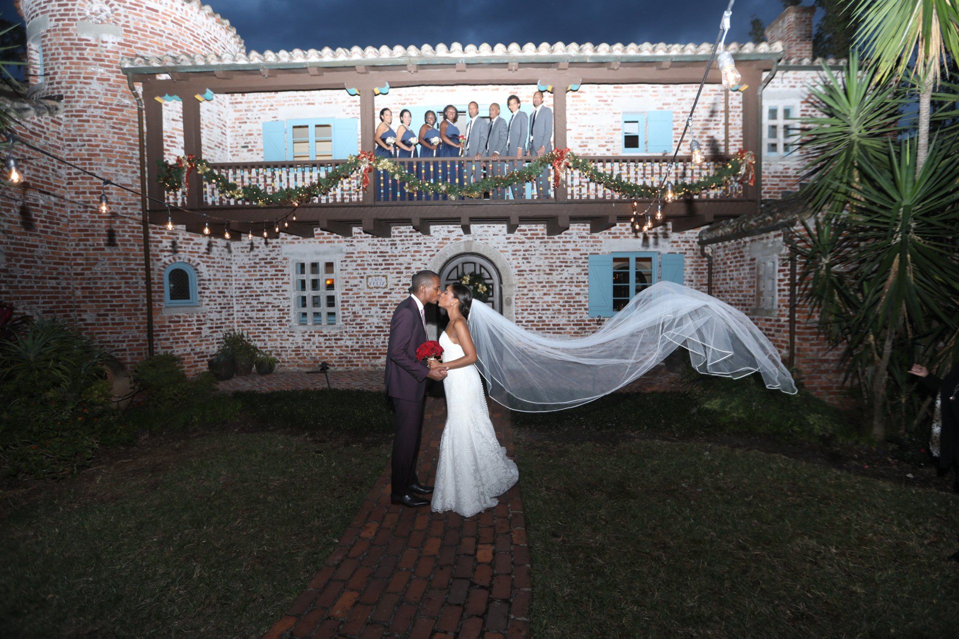 A bride and groom kissing in front of a brick building