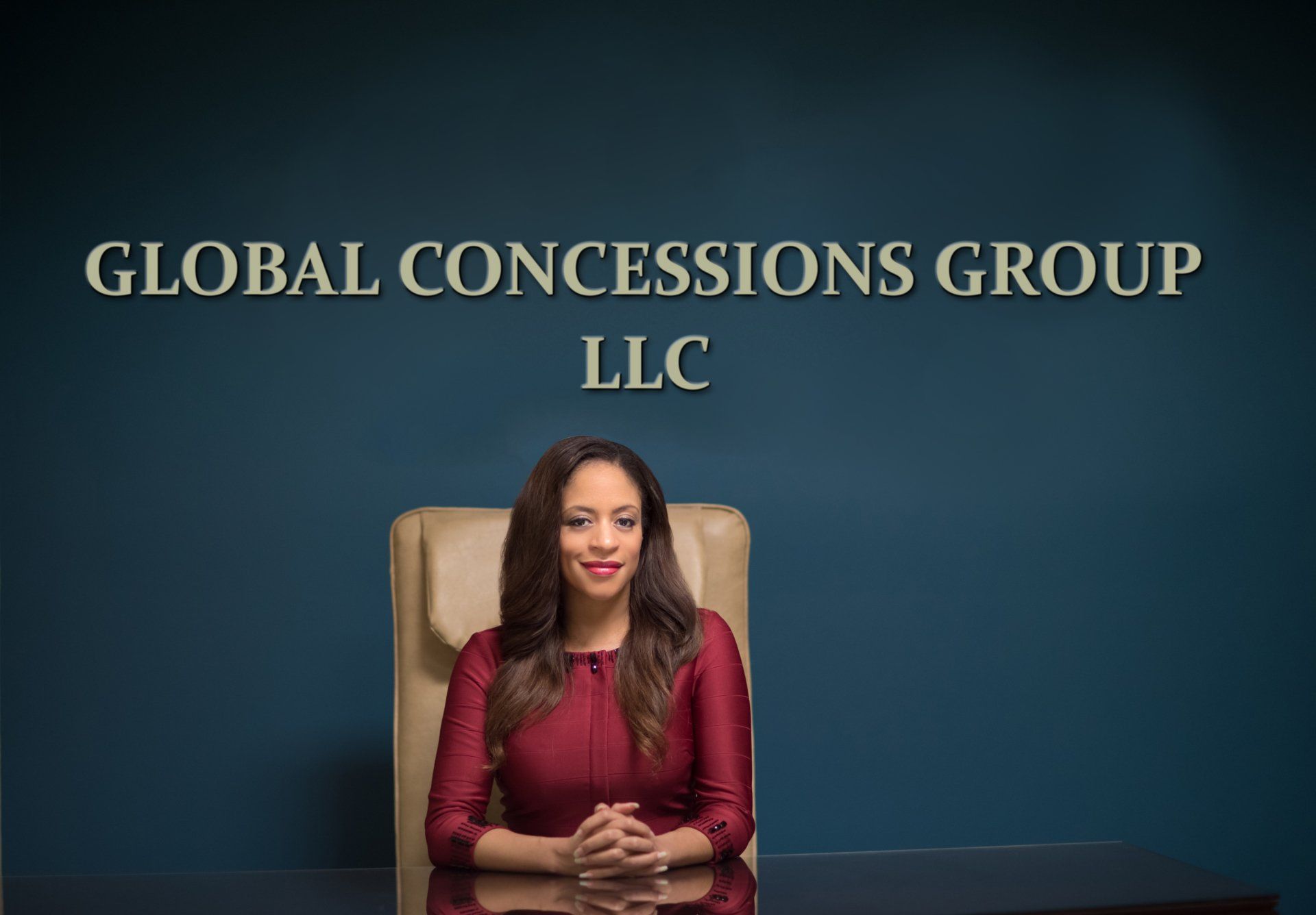 A woman is sitting at a desk in front of a wall that says global concessions group llc.
