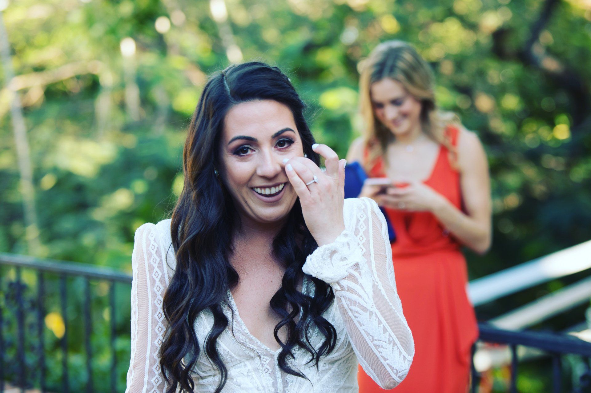 A woman in a white dress is crying while a woman in an orange dress looks on.