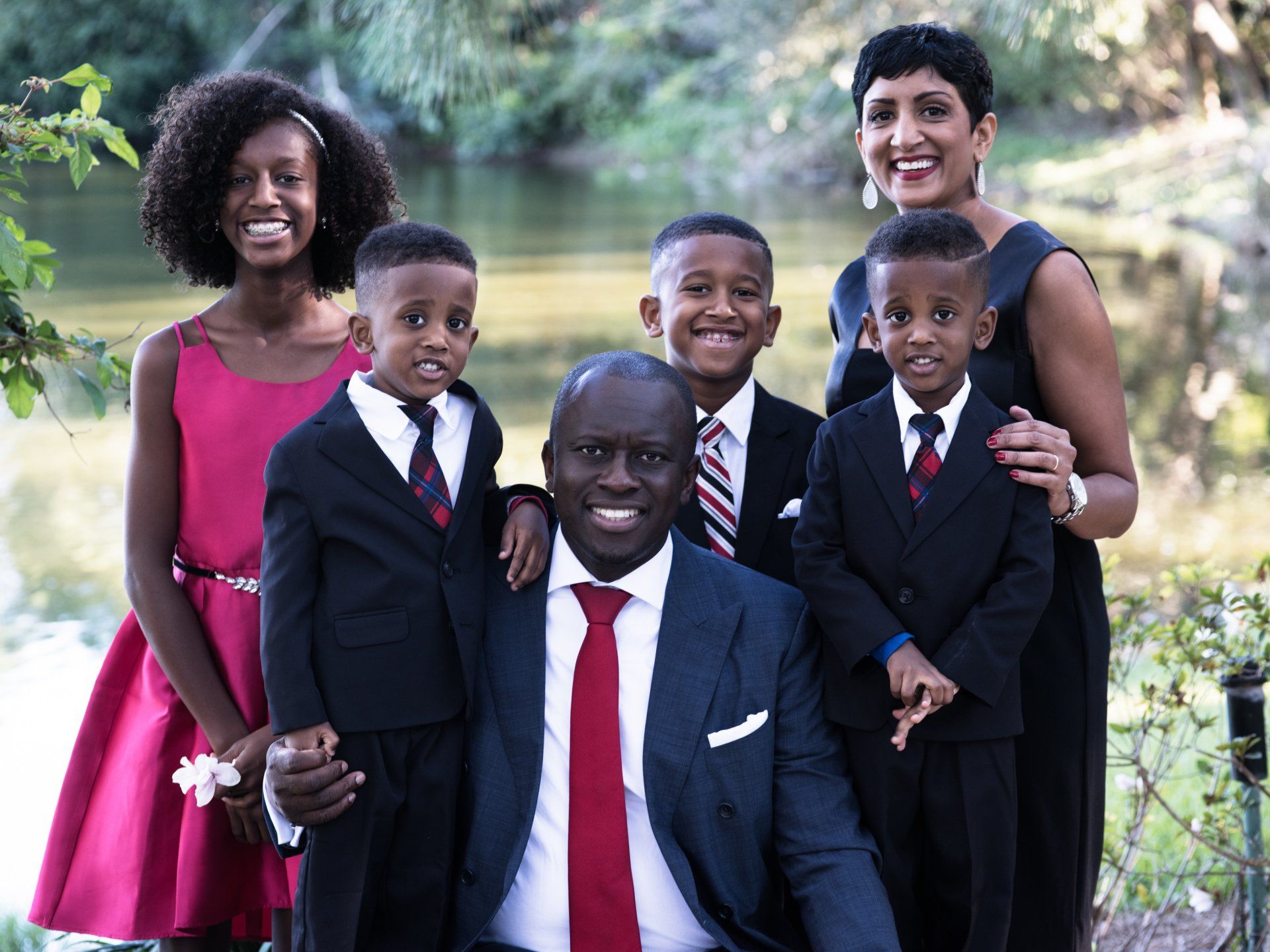 A man in a suit and tie is posing for a picture with his family.