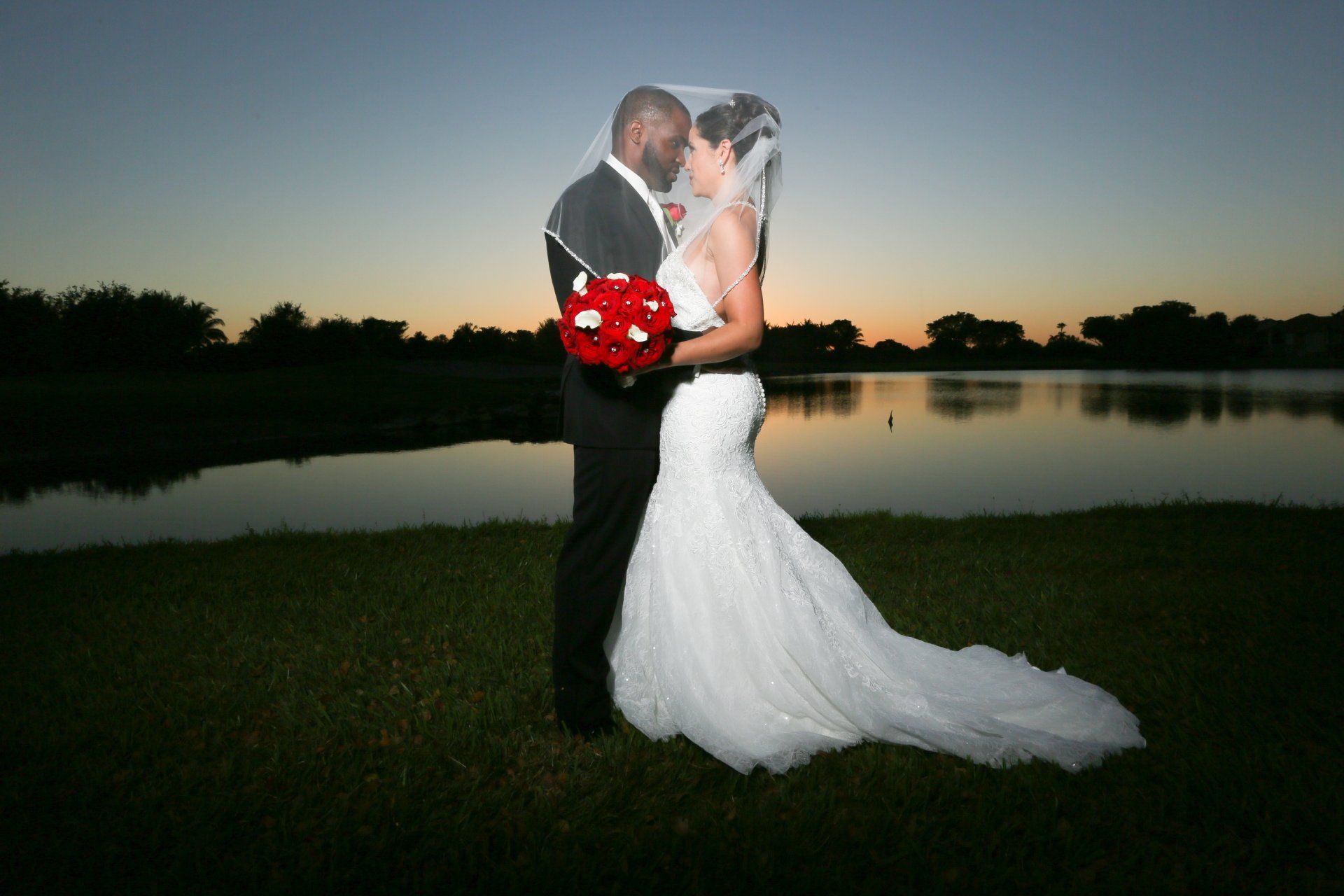 A bride and groom kissing in front of a lake