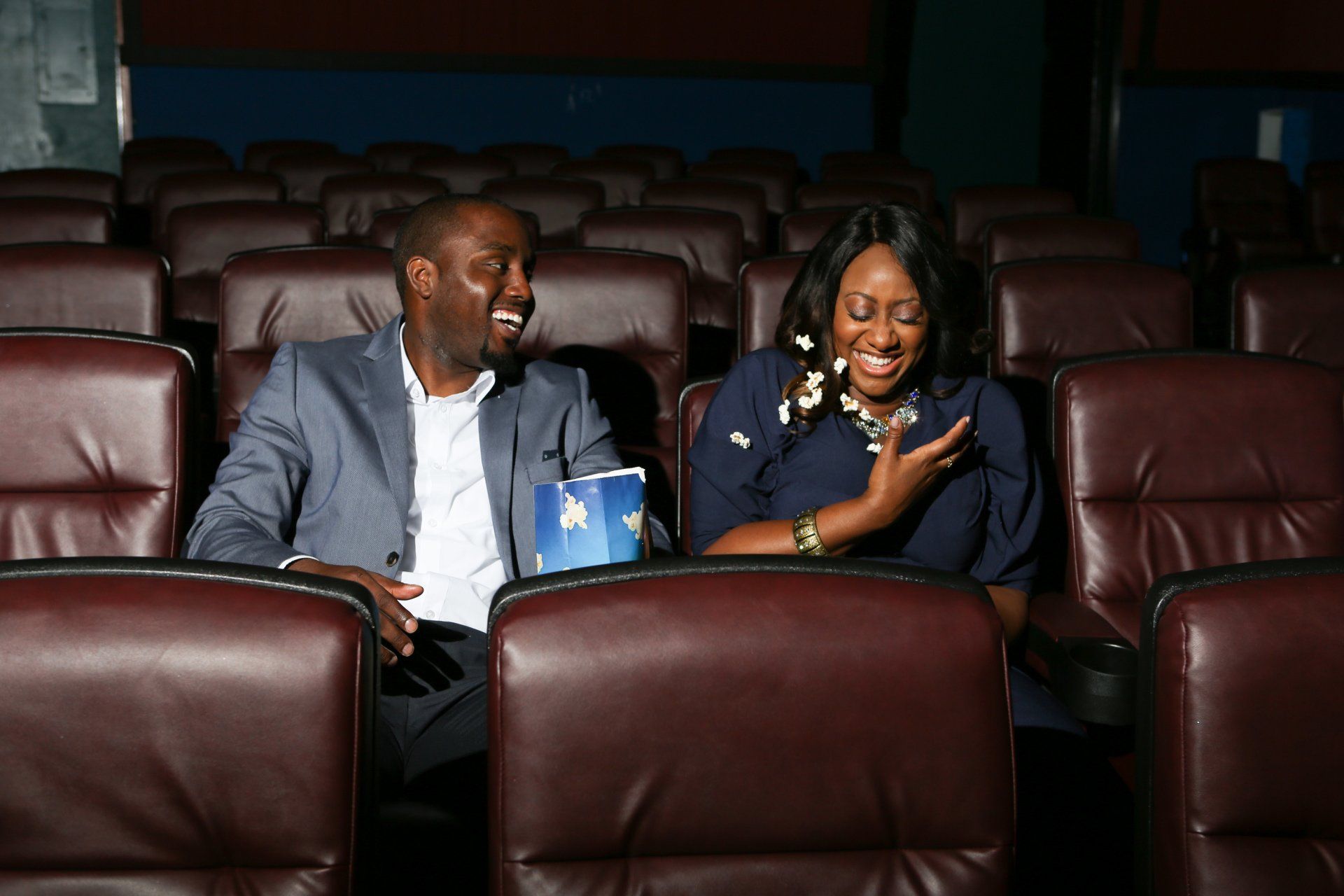 A man and a woman are sitting in a theater watching a movie.