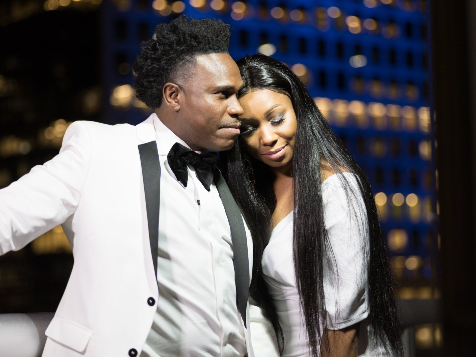 A man in a tuxedo and a woman in a white dress are posing for a picture.