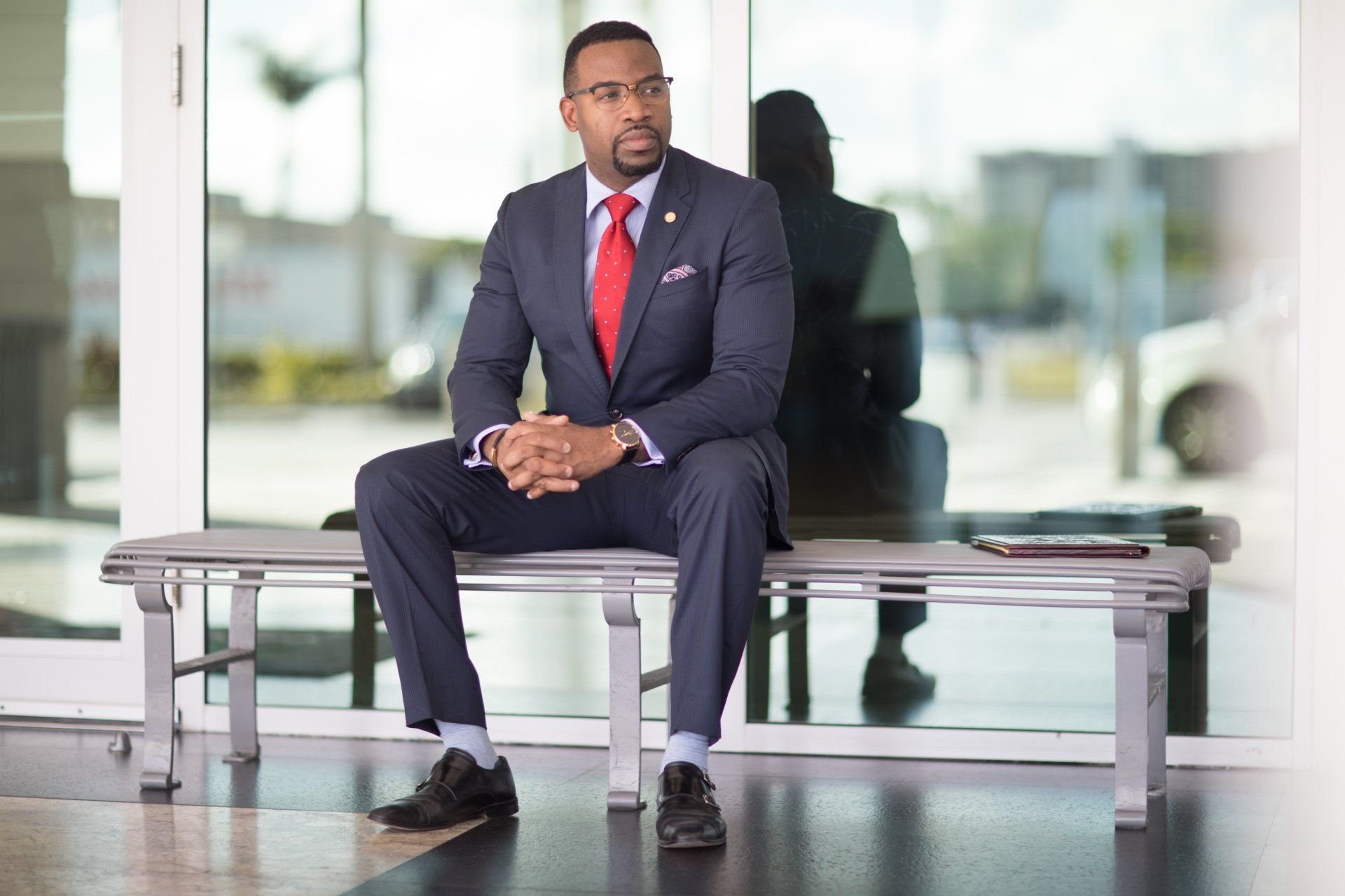 A man in a suit and tie is sitting on a bench.