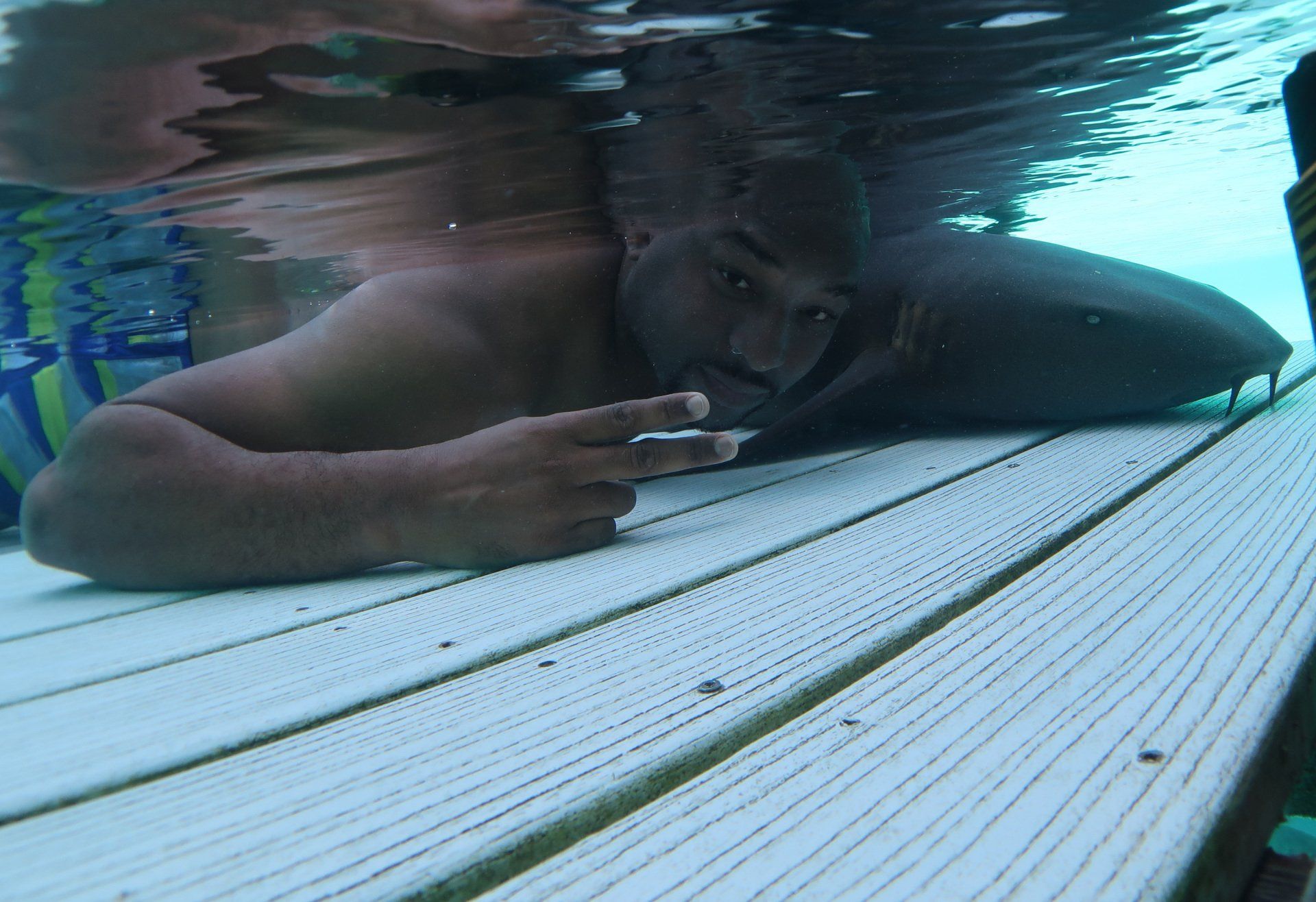 A man is laying on a wooden deck underwater