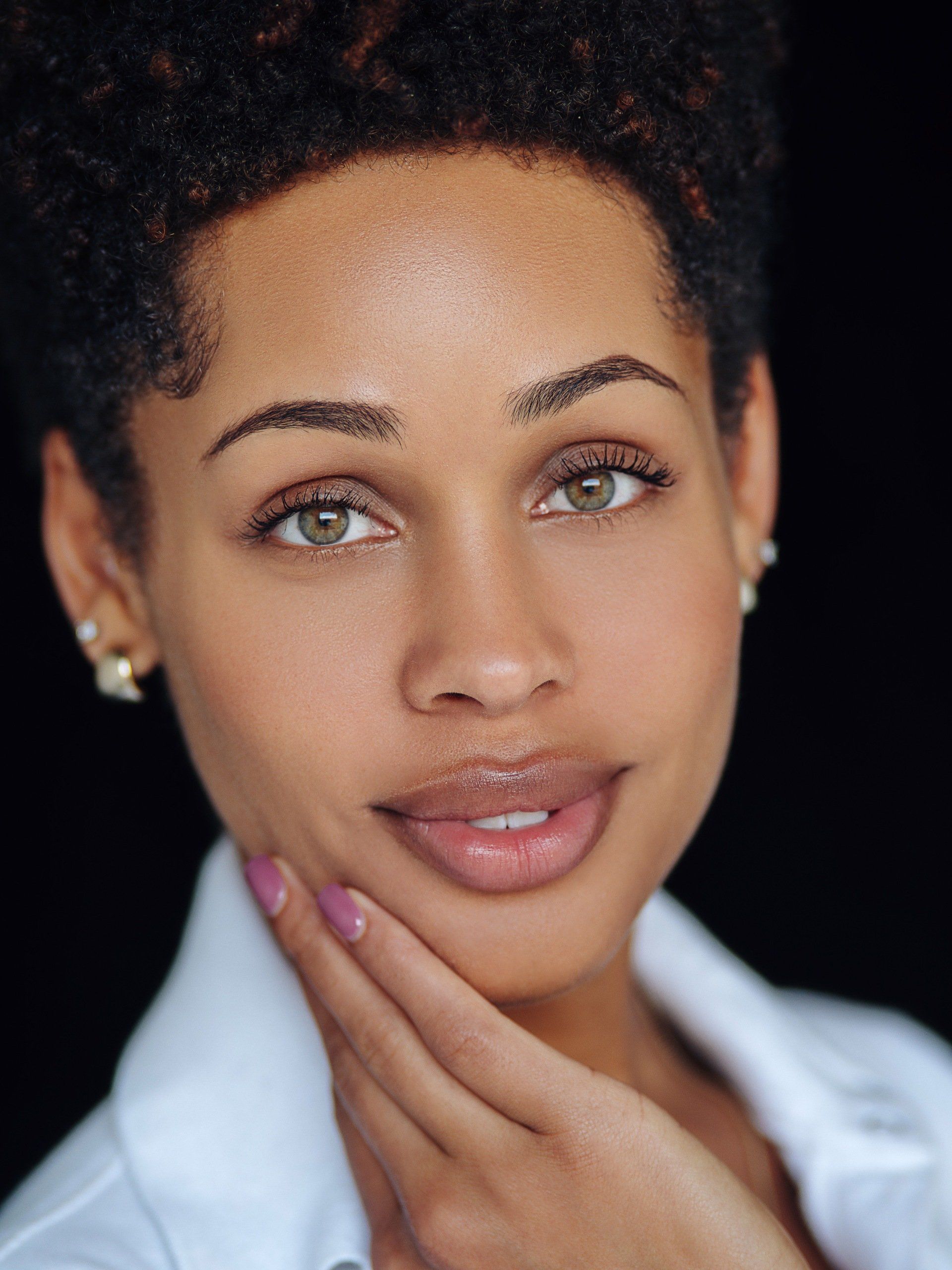 A close up of a woman 's face with her hand on her chin