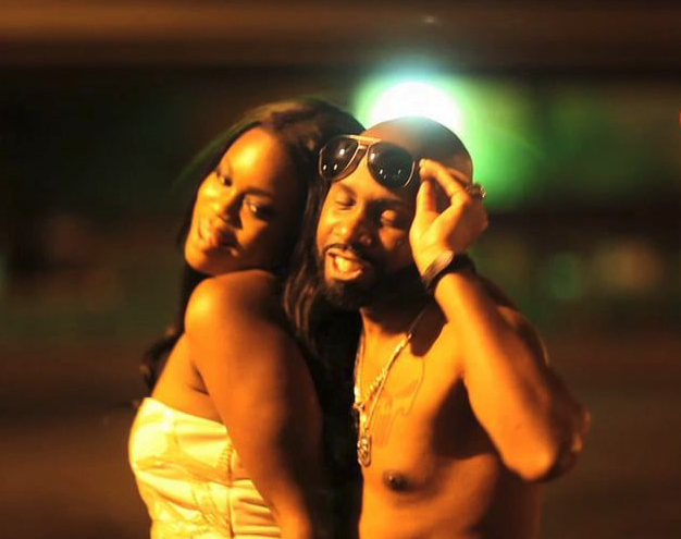 A man without a shirt is standing next to a woman wearing sunglasses