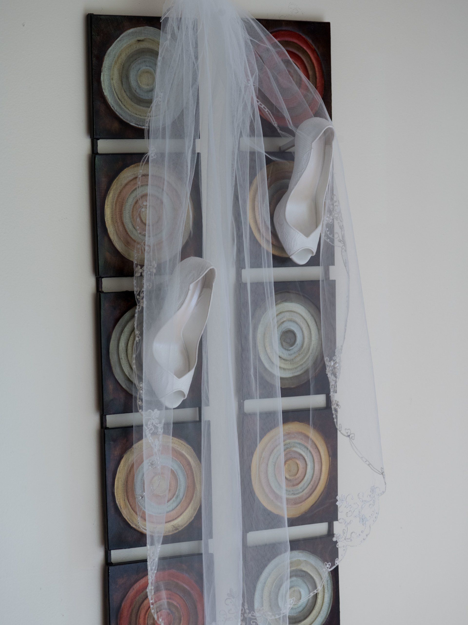 A veil is hanging on a wall next to a pair of shoes