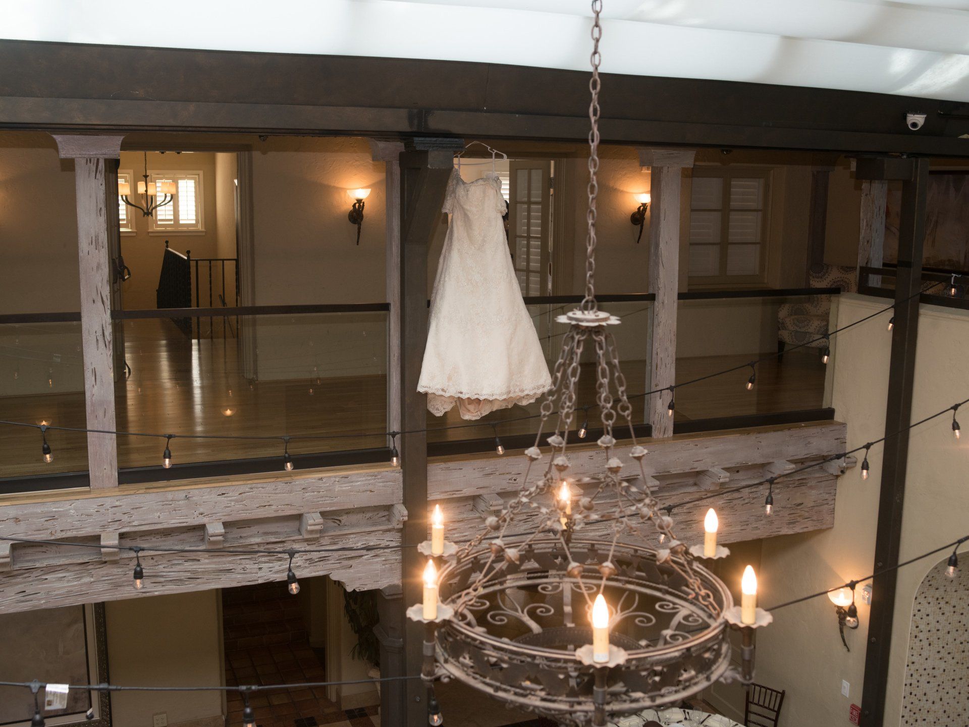 A wedding dress is hanging from a chandelier in a room.