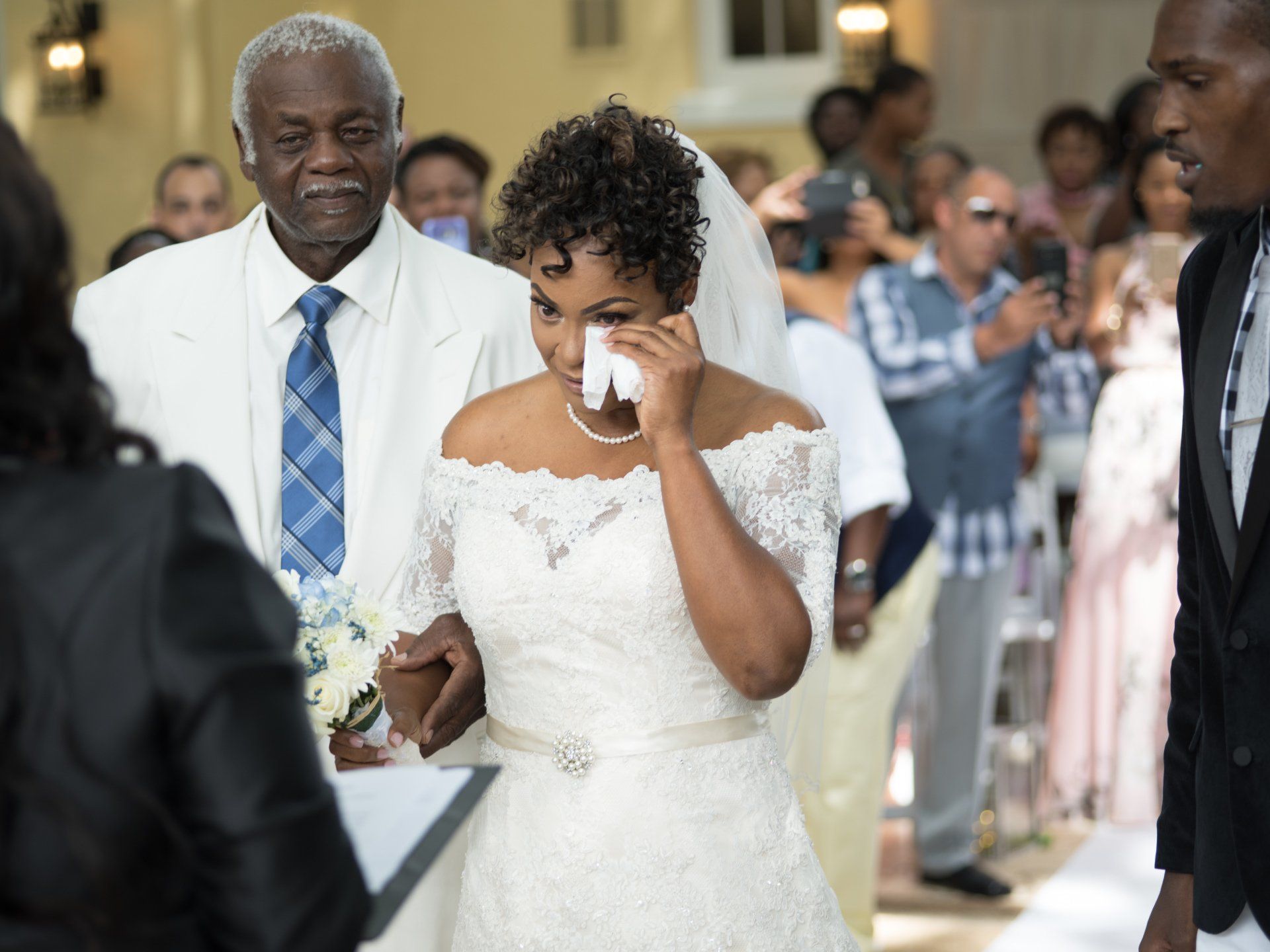 A bride is crying while walking down the aisle at her wedding