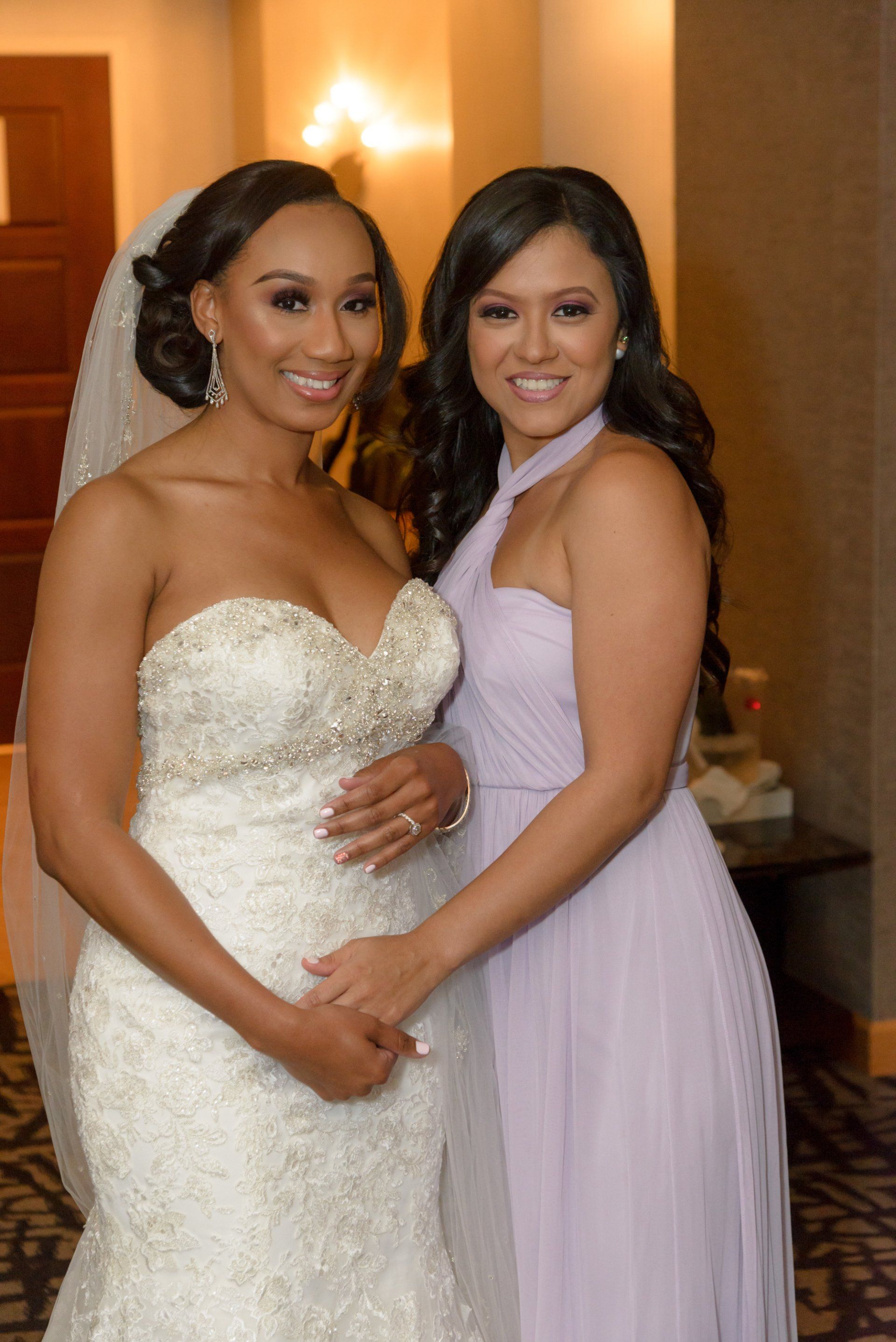 A bride and her bridesmaid are posing for a picture together.