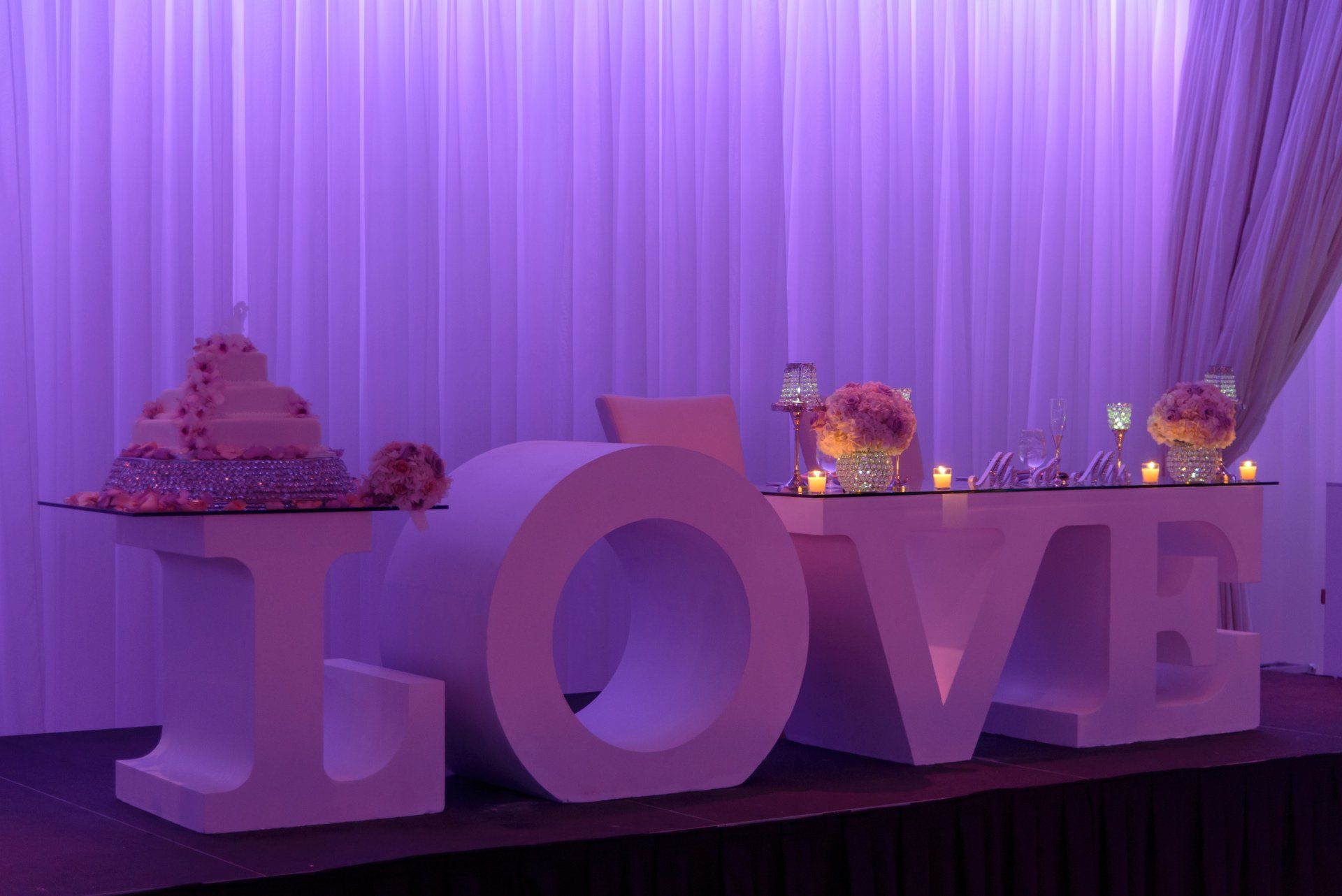 A wedding table with a cake and a love sign on it.