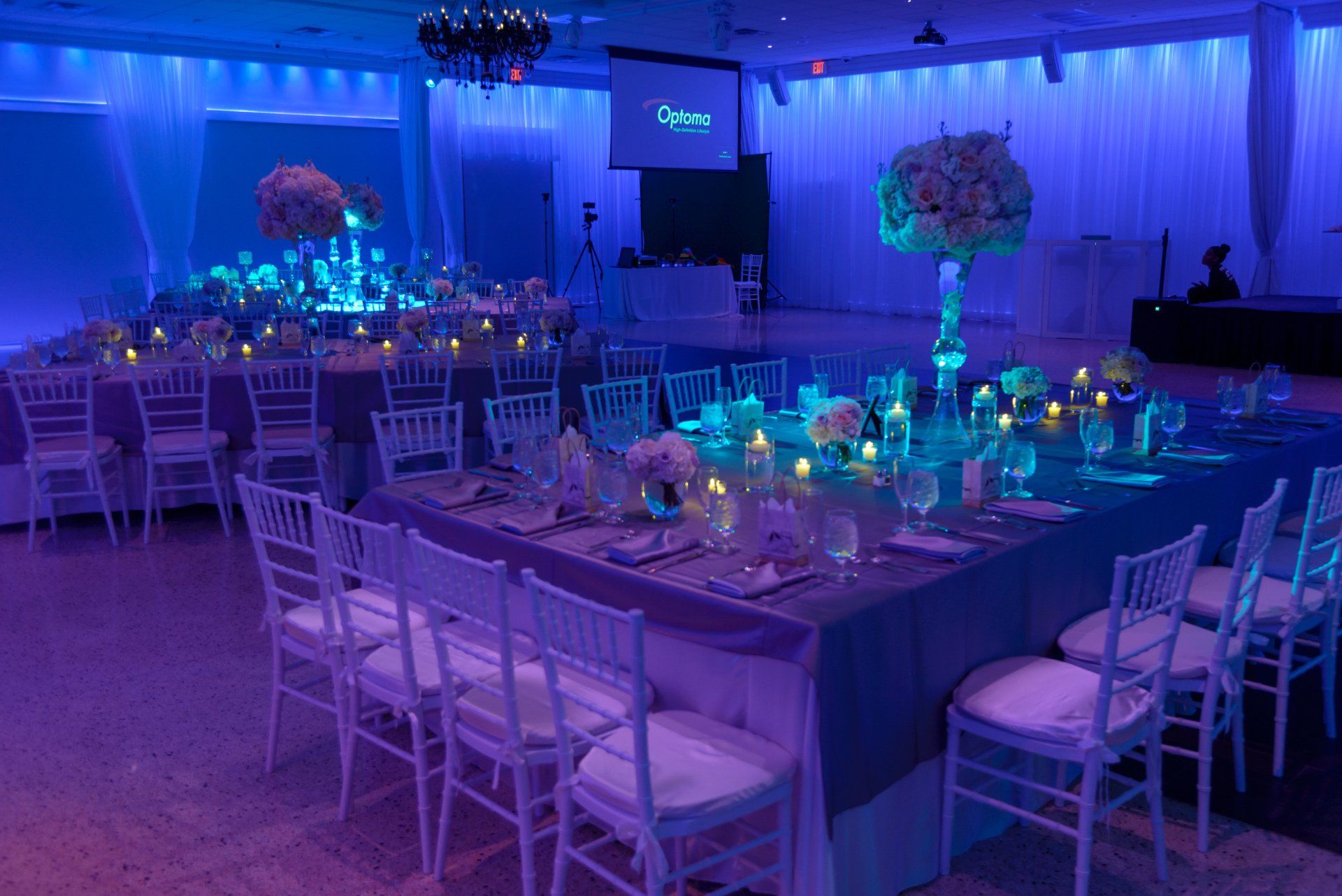 A large room with tables and chairs set up for a wedding reception.